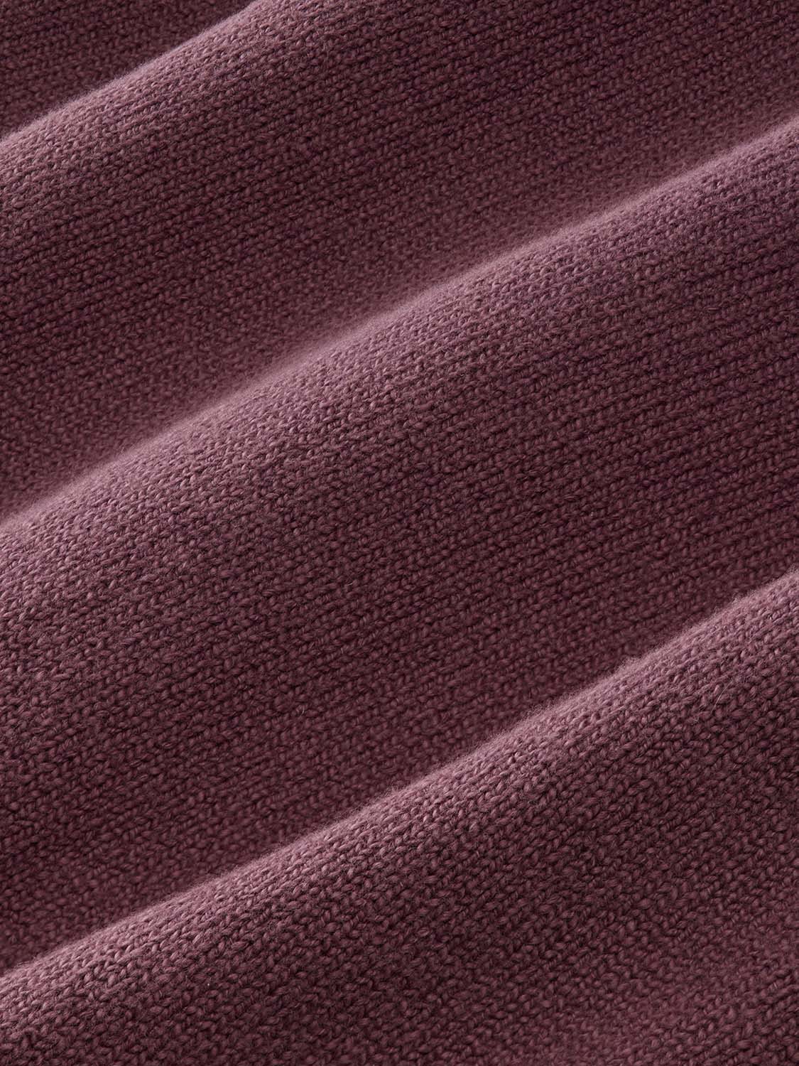 Burgundy knit sweater fabric with a textured waffle weave pattern and diagonal folds.