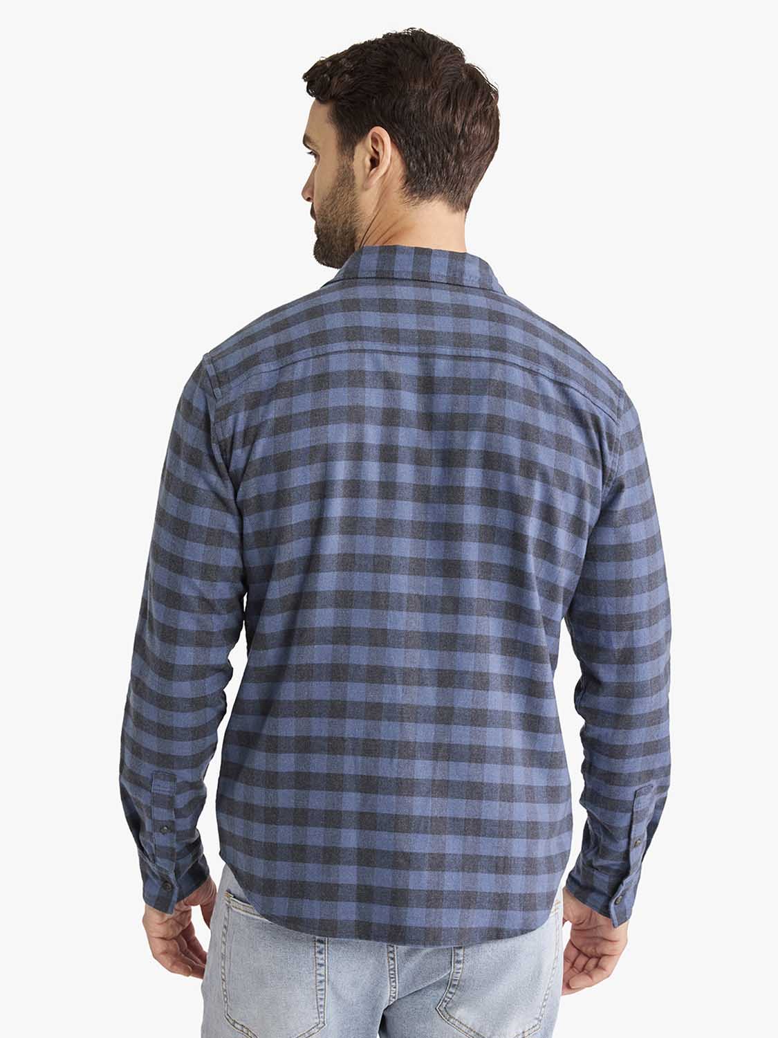 Man wearing a blue and gray checked flannel shirt with long sleeves, shown from the back.