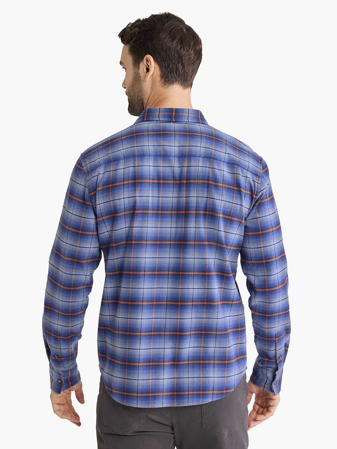 Man wearing a blue plaid flannel shirt with orange and white stripes over gray pants.