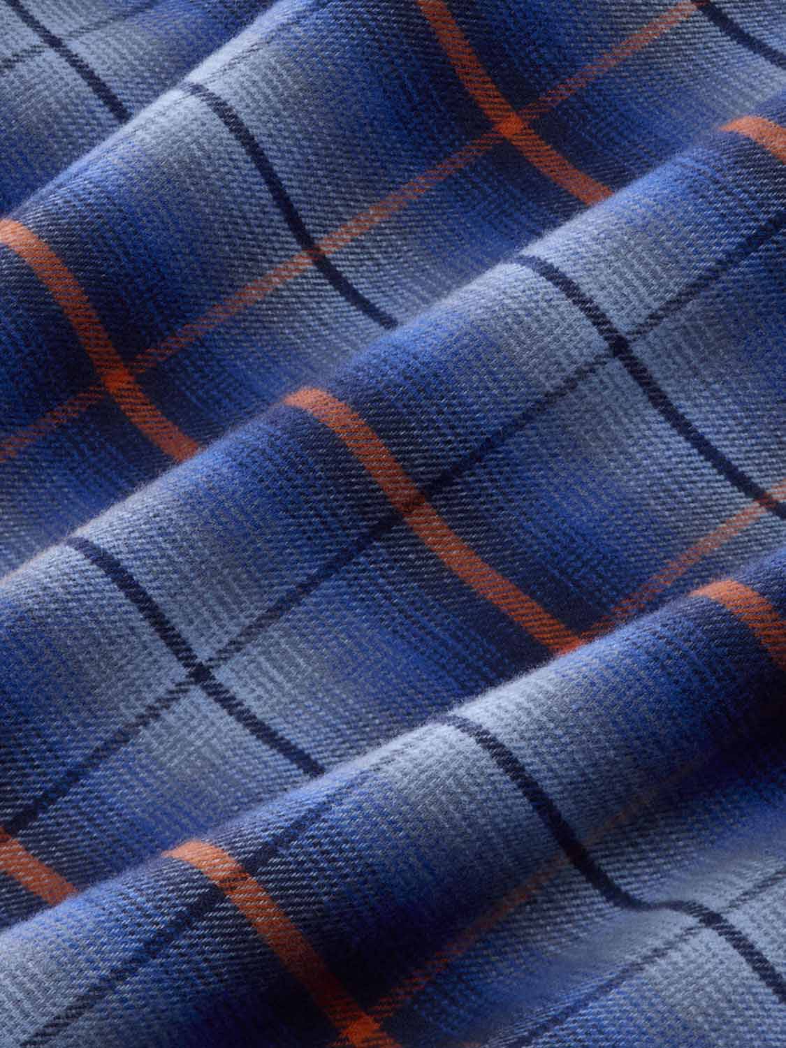 Close-up of blue plaid flannel fabric with orange and white woven stripes throughout.