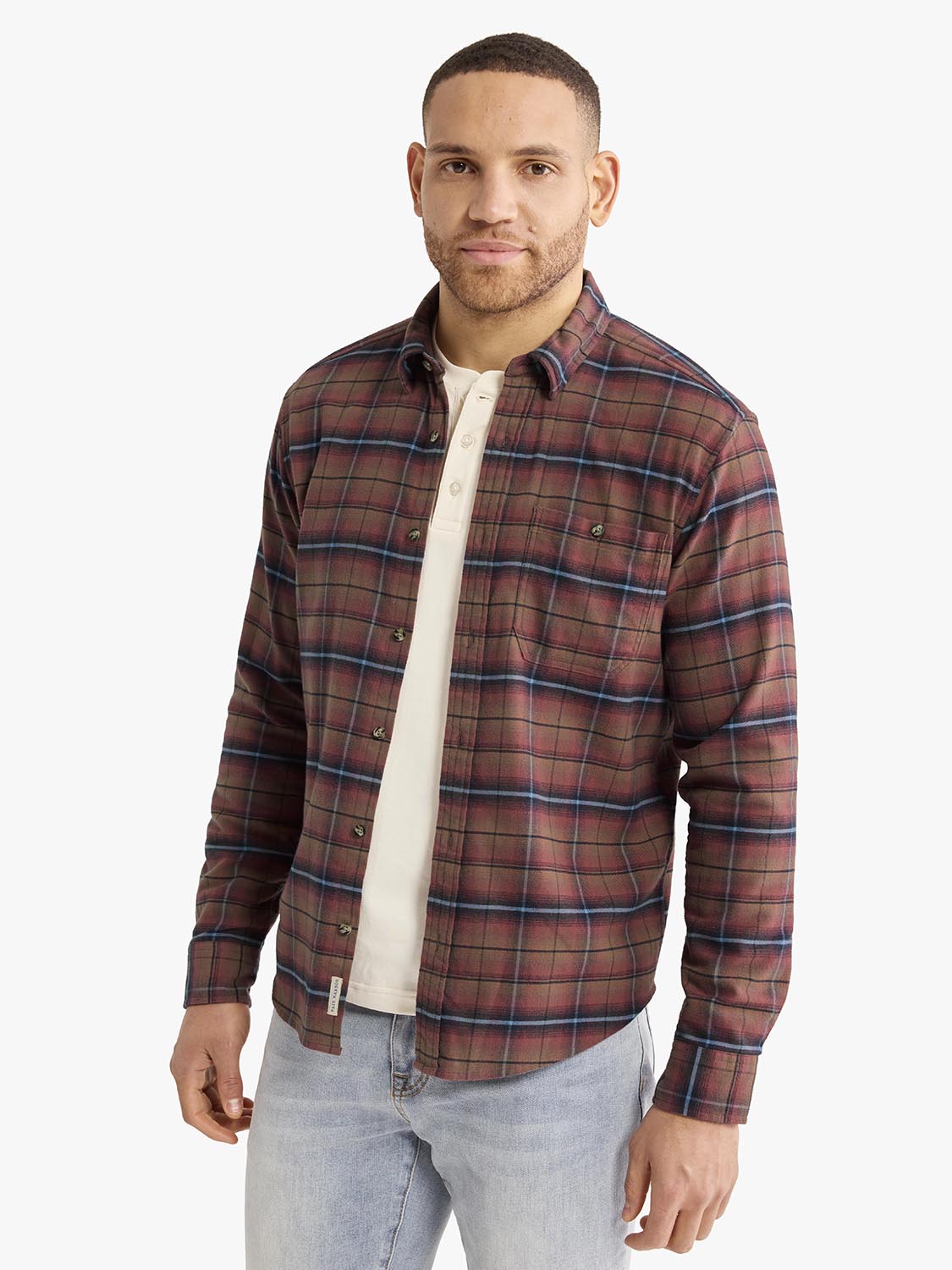 Man wearing burgundy plaid flannel shirt with navy stripes over white undershirt.