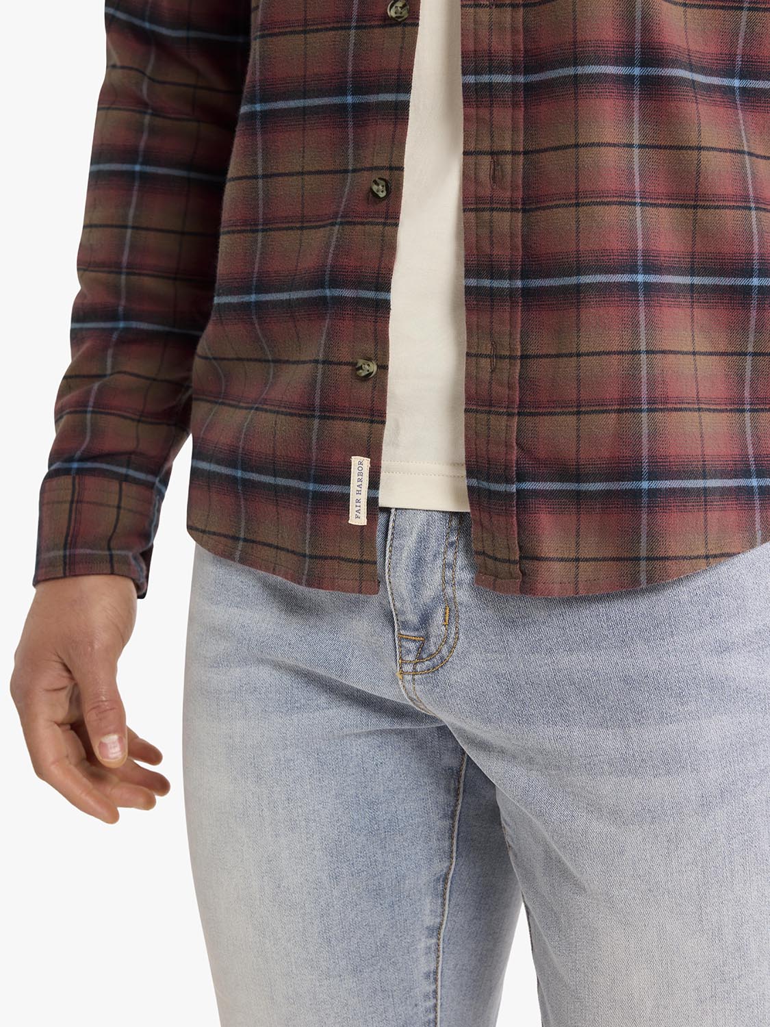 Burgundy plaid flannel shirt with navy and blue stripes worn over a cream undershirt and light blue jeans.