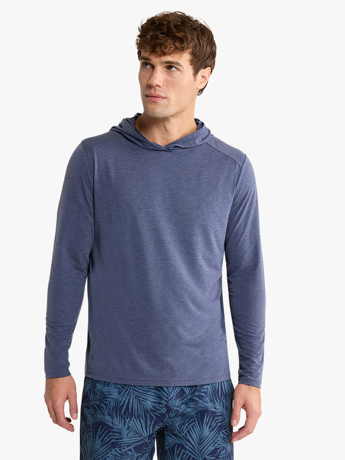 Man wearing a navy blue hoodie with long sleeves standing against a white background.