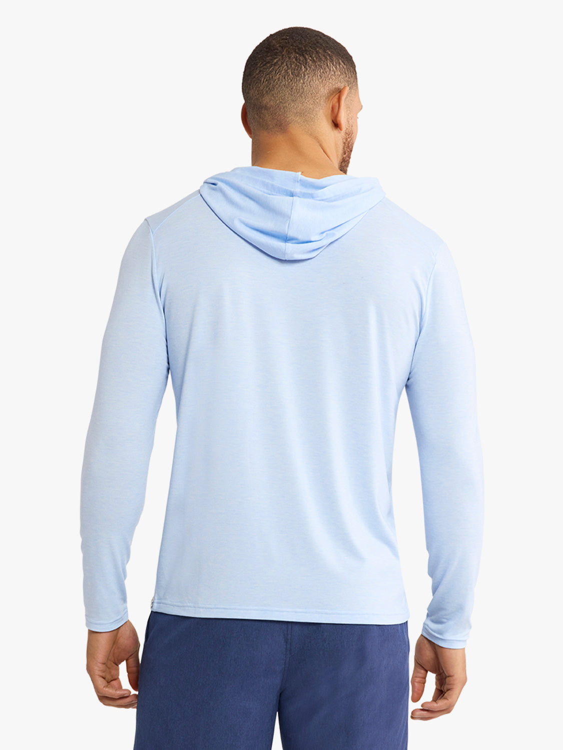 Man wearing light blue hoodie with attached hood viewed from back against white background.