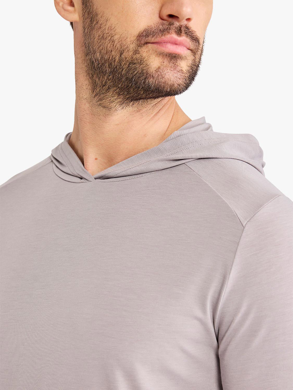 Man wearing a light gray hoodie with a relaxed fit and drawstring hood detail.
