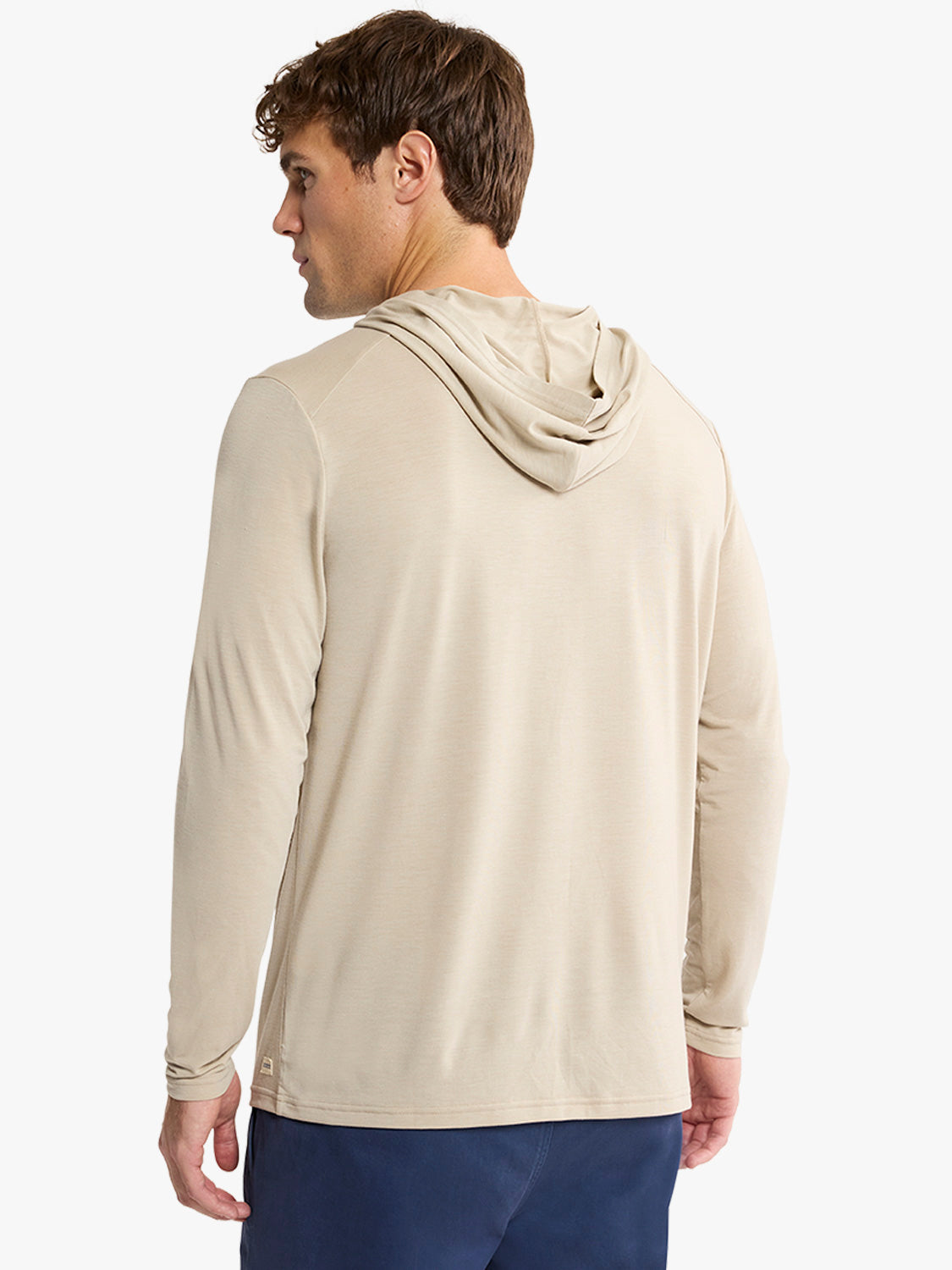 Man wearing a sand-colored hoodie with long sleeves, shown from the back view.