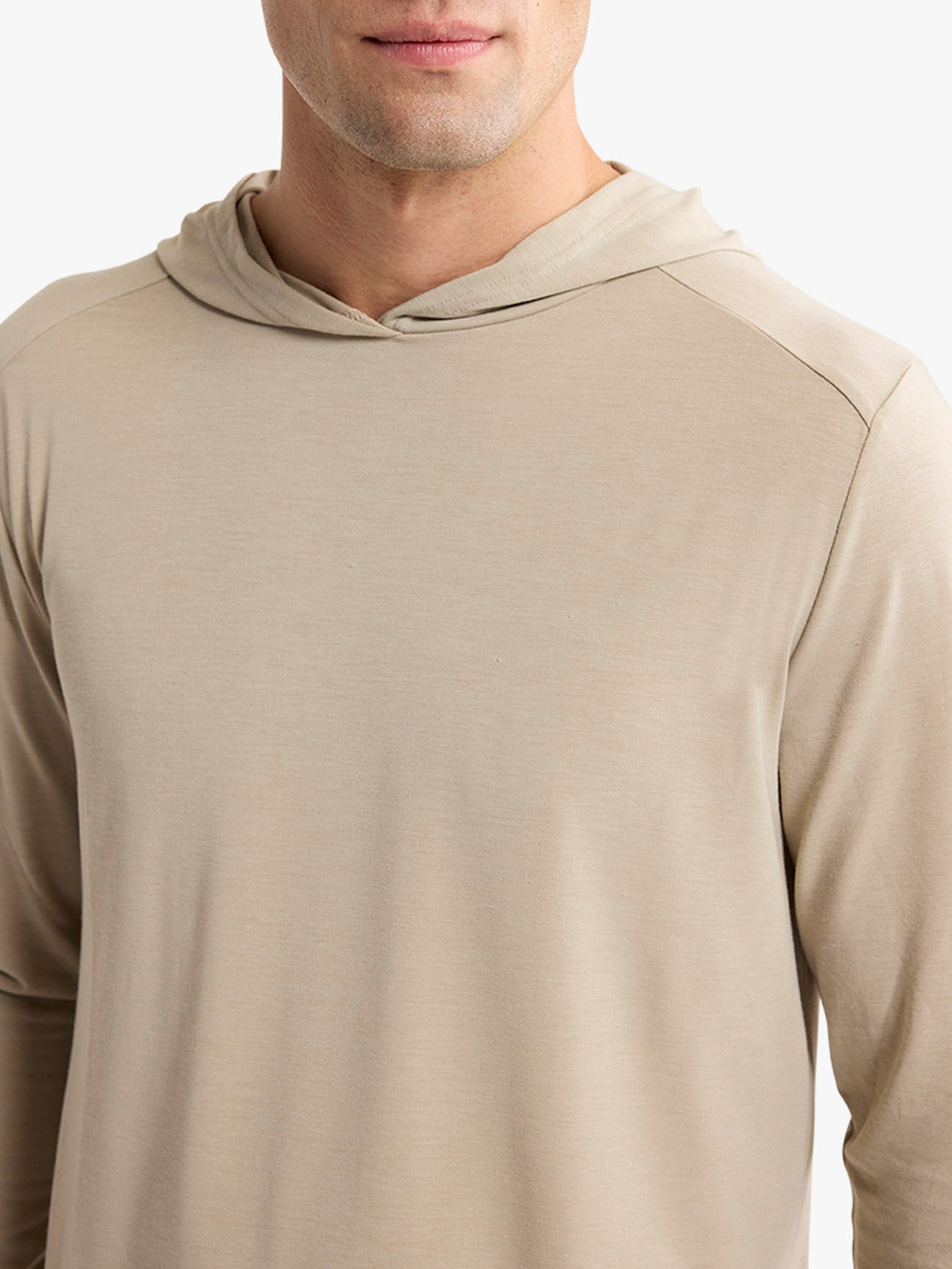 Man wearing a sand-colored hoodie with long sleeves and a drawstring hood.