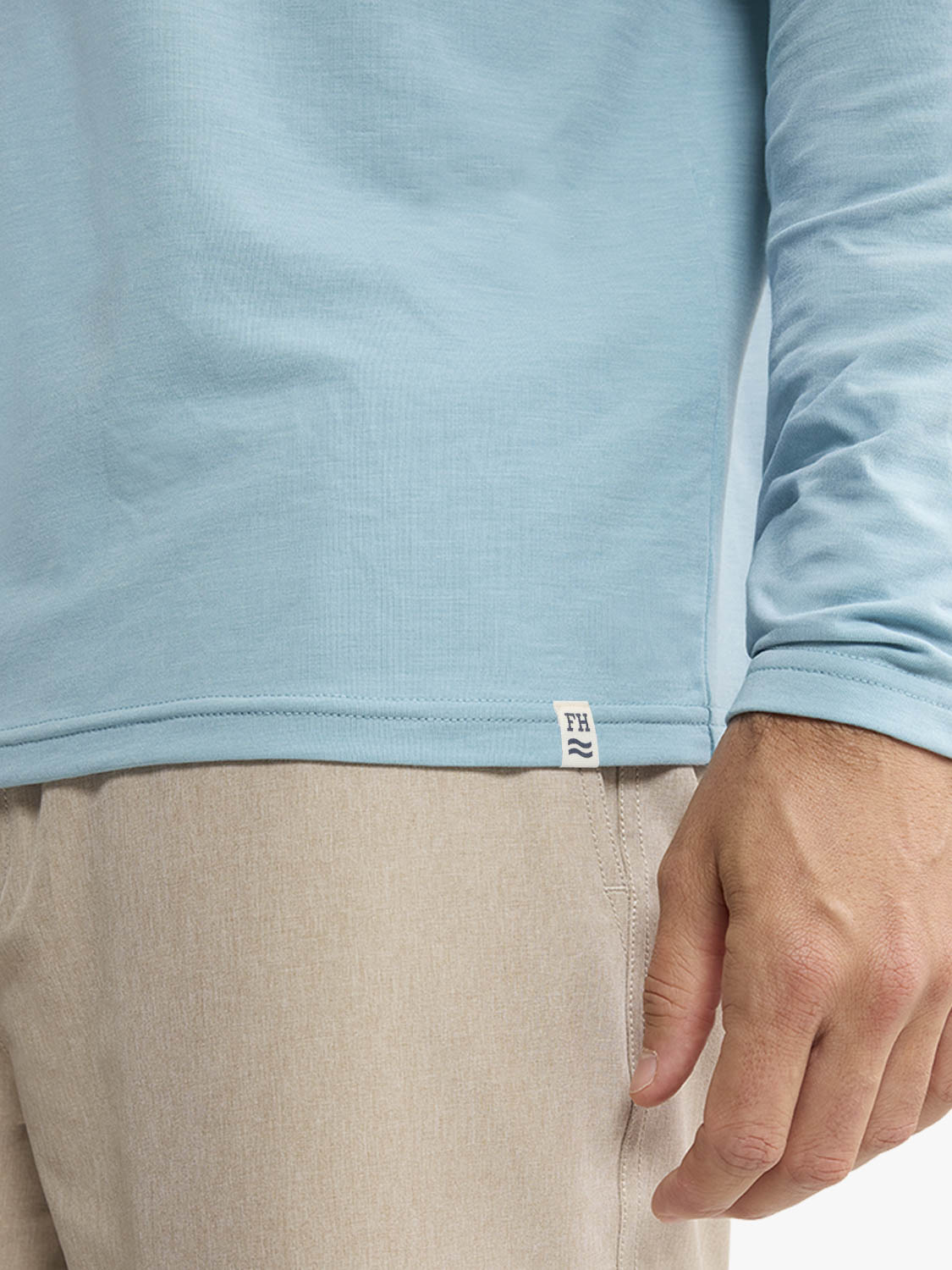 Light blue hoodie with ribbed cuffs and a small branded label visible at the hem.