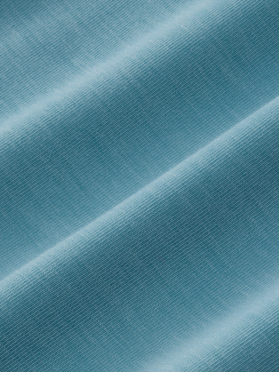 Bay blue textured fabric with diagonal folds and soft lighting creating shadow gradients.