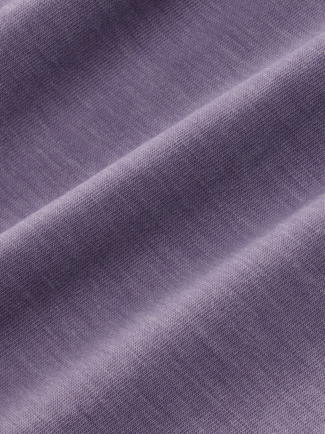 Close-up of a dusk purple textured hoodie fabric showing diagonal folds and weave detail.