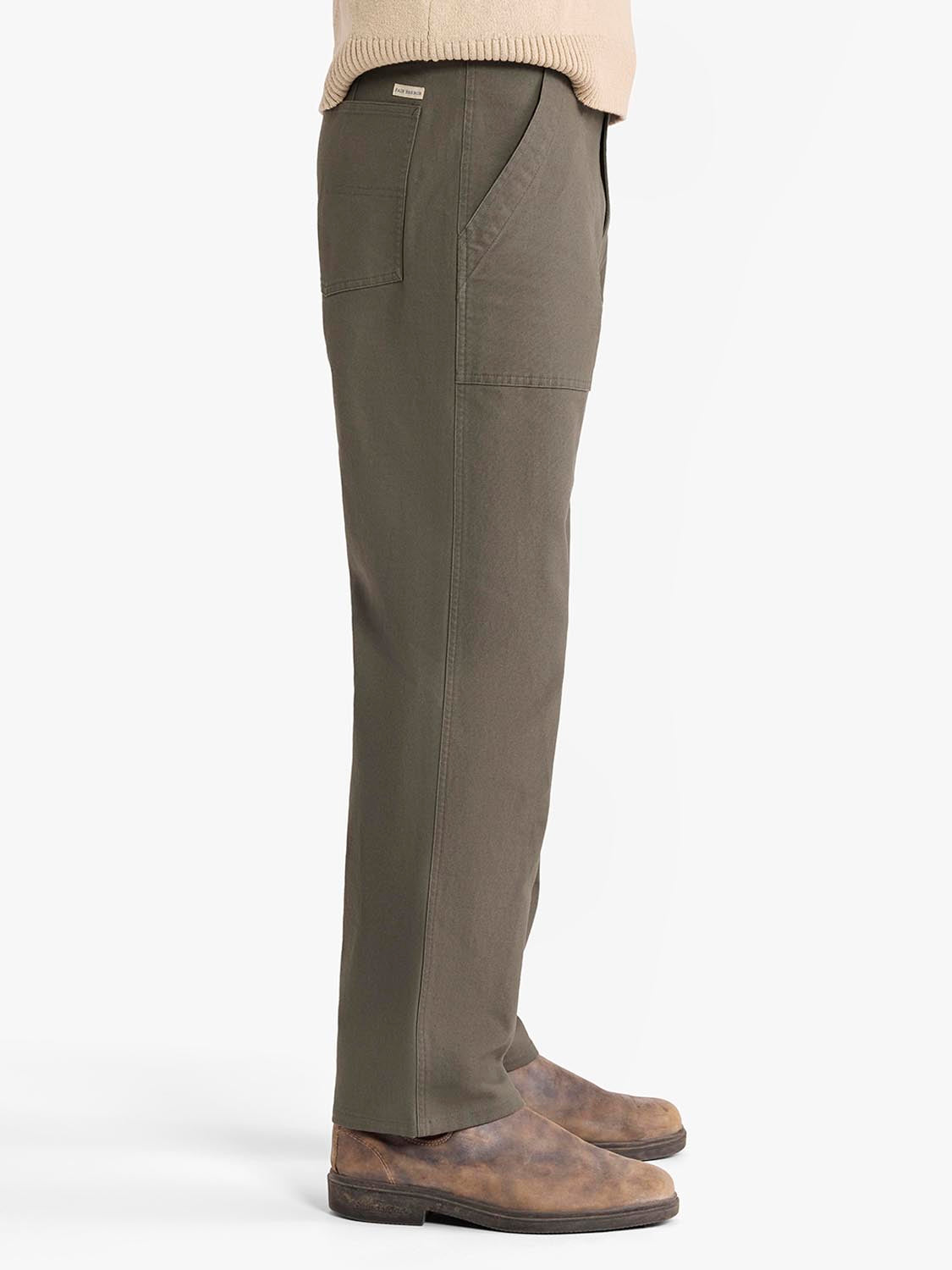 Olive-colored cargo pants with side pockets worn with a cream sweater and brown suede shoes.