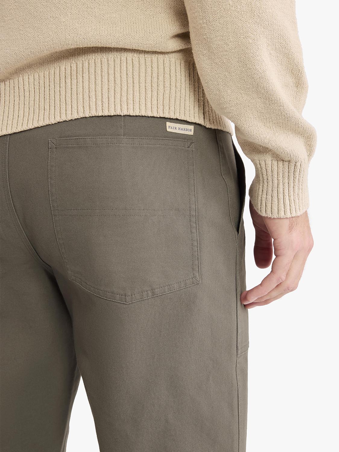 Person wearing olive-colored pants with a back pocket and beige sweater visible at waist.