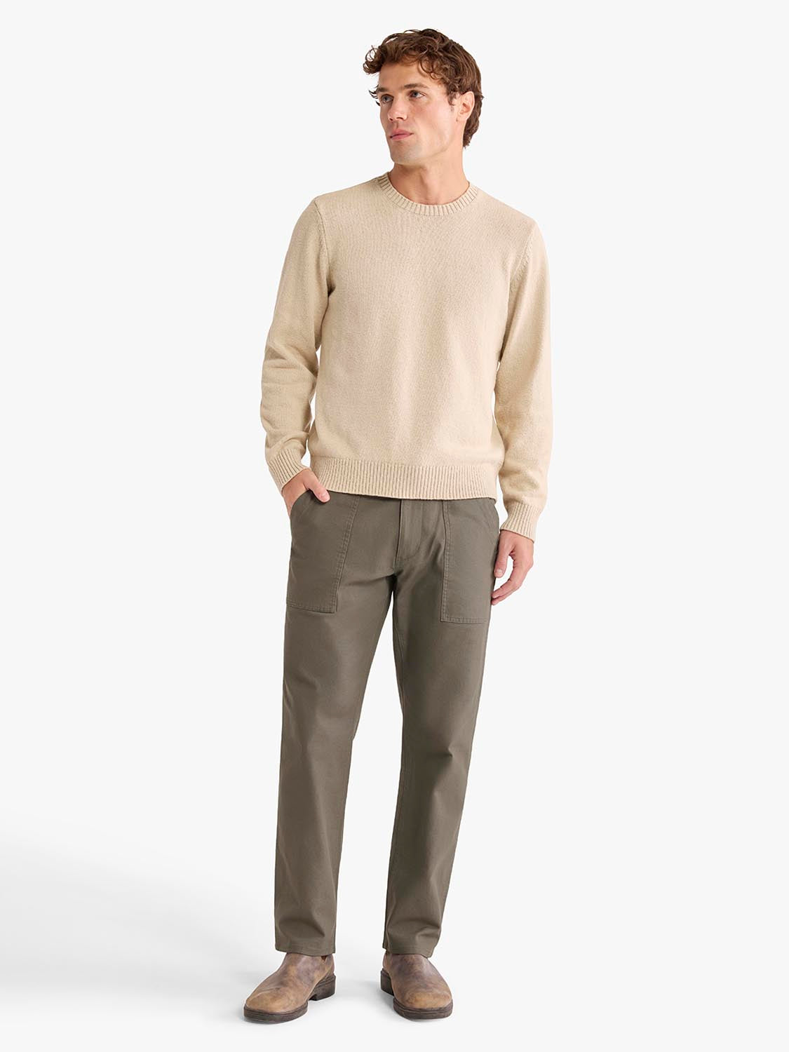 Man wearing a cream knit sweater and olive utility pants with patch pockets.