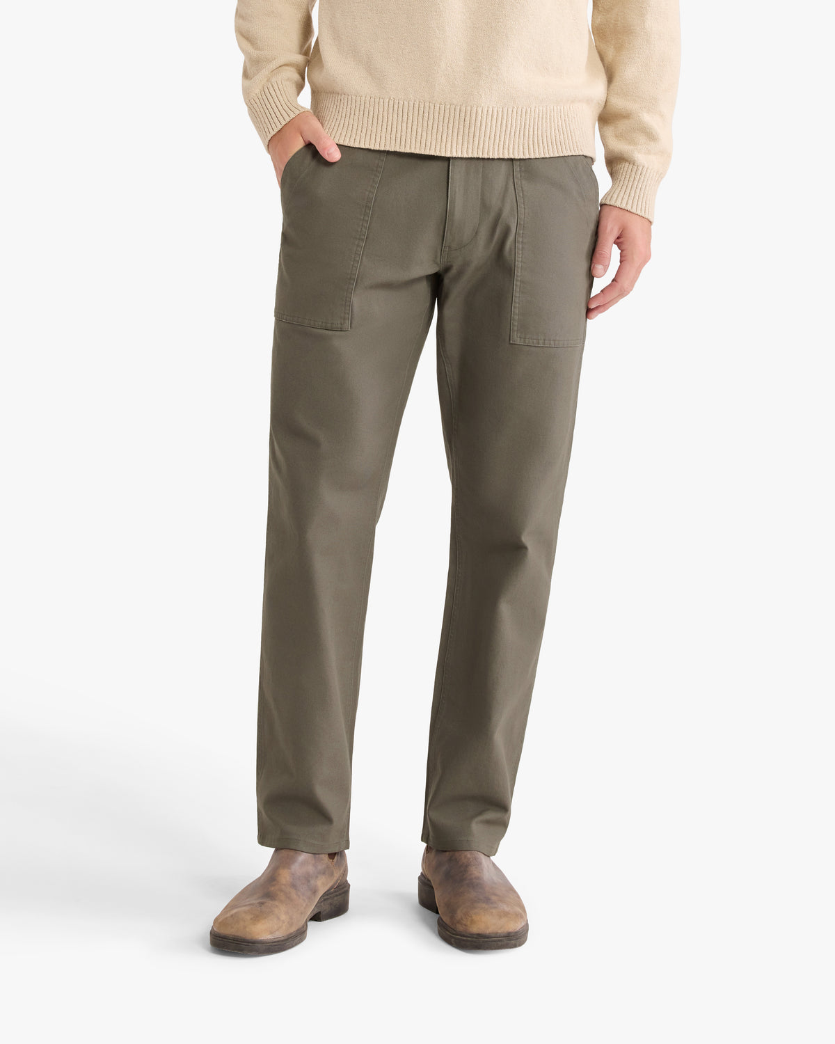 Olive pants with front patch pockets and elastic waistband worn with a cream sweater and brown boots.