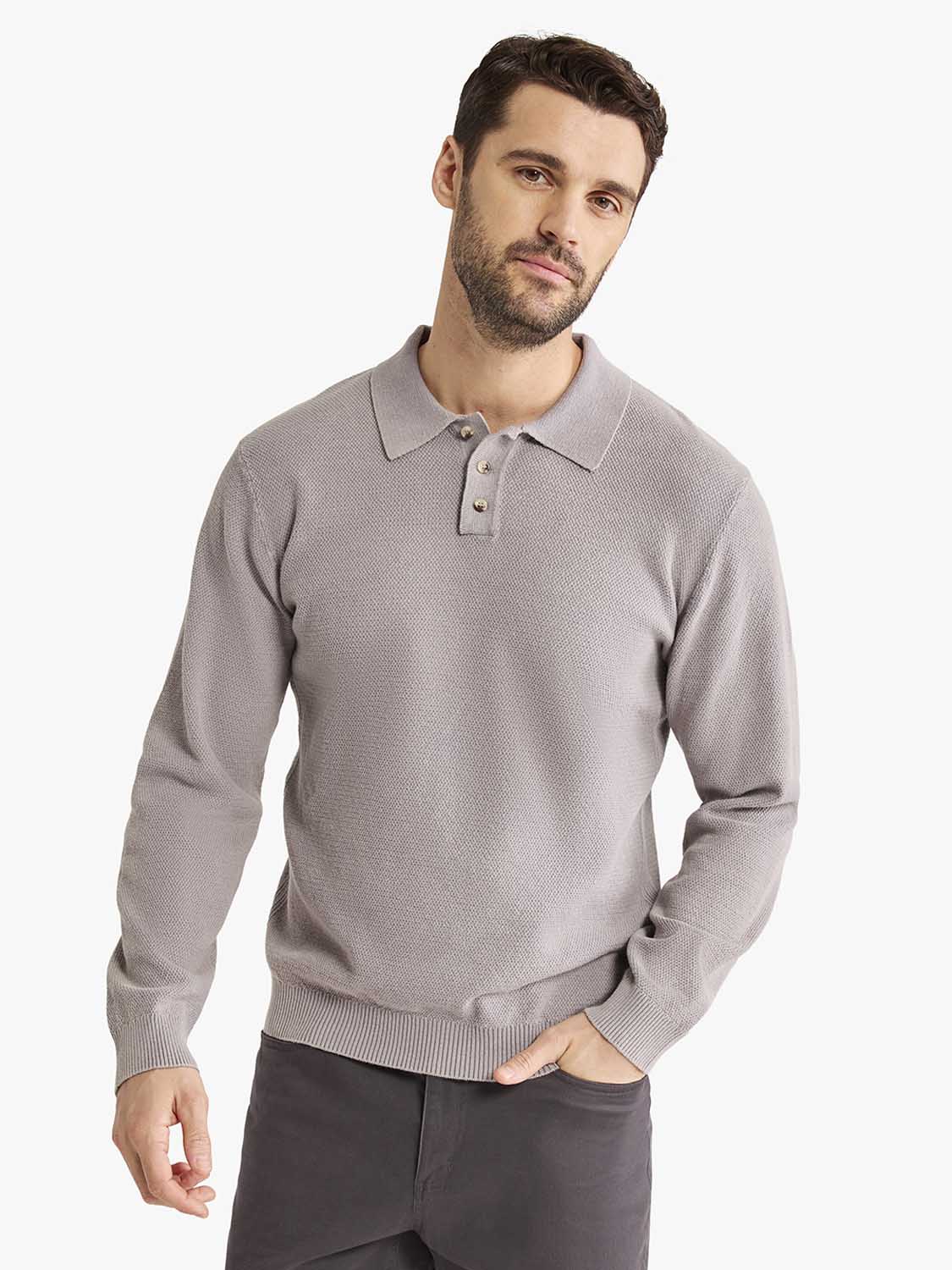 Man wearing a light gray long sleeve polo shirt with a textured knit fabric and button placket.