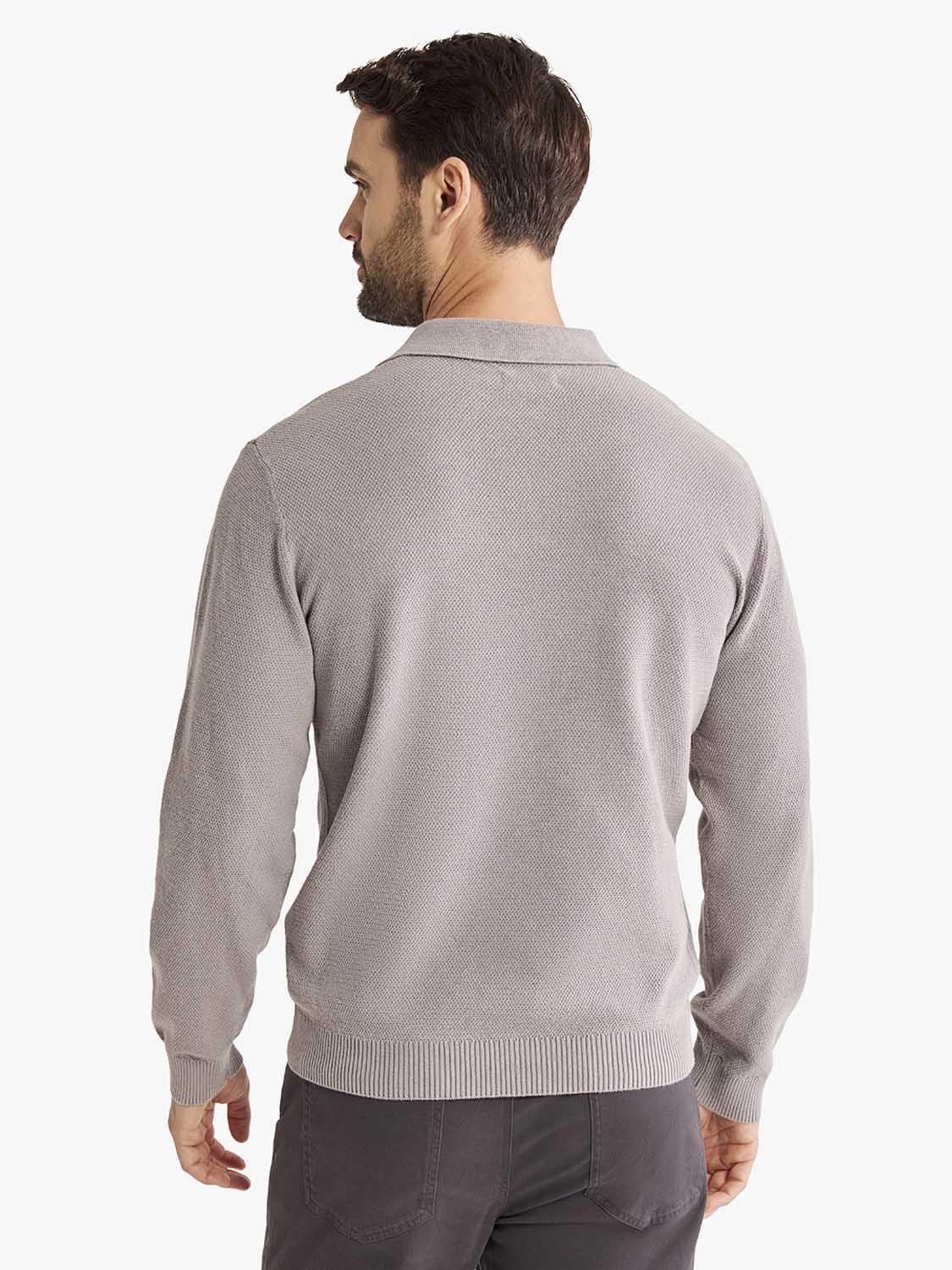 Man wearing a light gray long sleeve polo shirt with a textured knit fabric and collar, shown from the back.