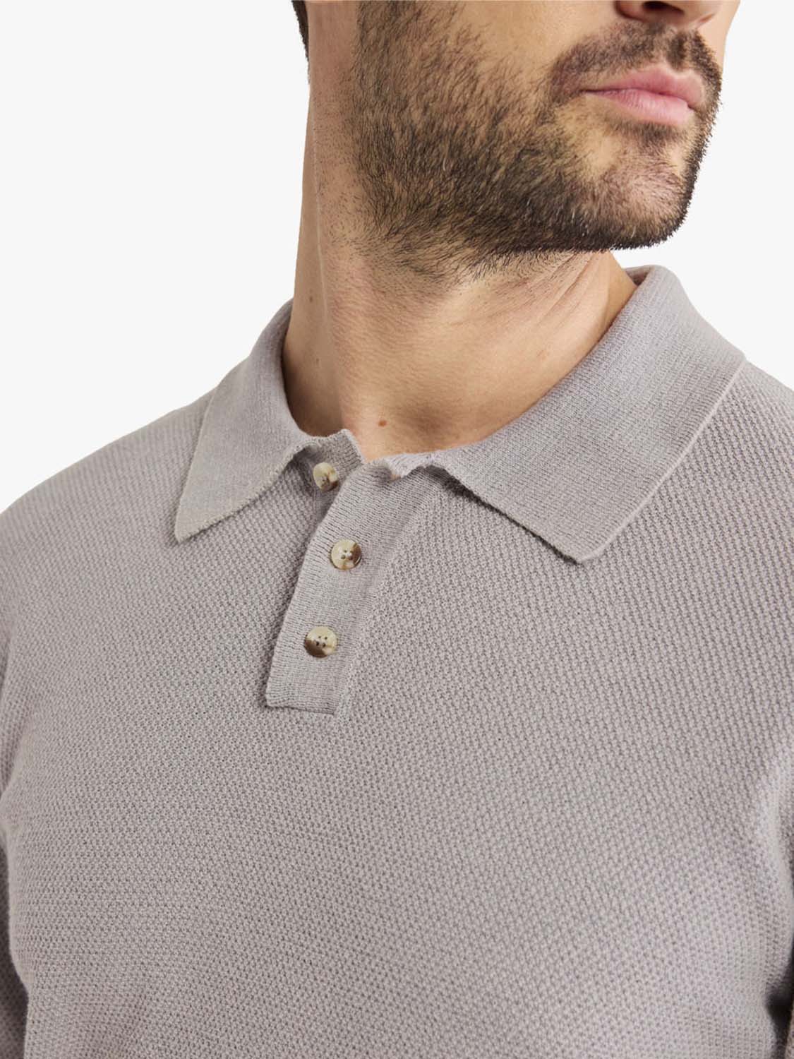 Man wearing a light gray long sleeve polo shirt with a ribbed texture and button placket.