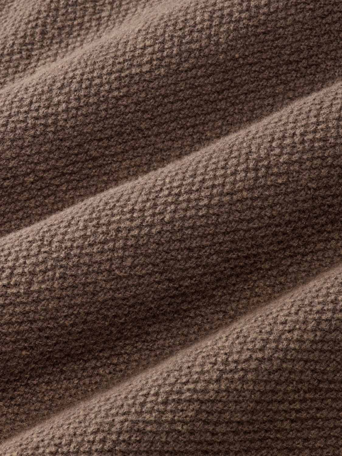 Close-up of espresso brown textured fabric with diagonal folds creating depth and shadow.