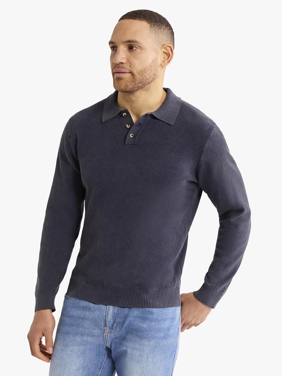 Man wearing a navy long sleeve polo shirt with a textured knit fabric and button placket.