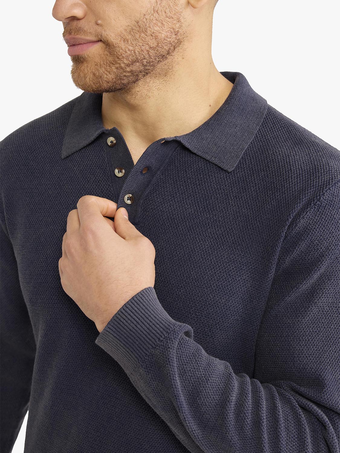 Man wearing a navy long sleeve polo shirt with a collared neckline and button front closure.