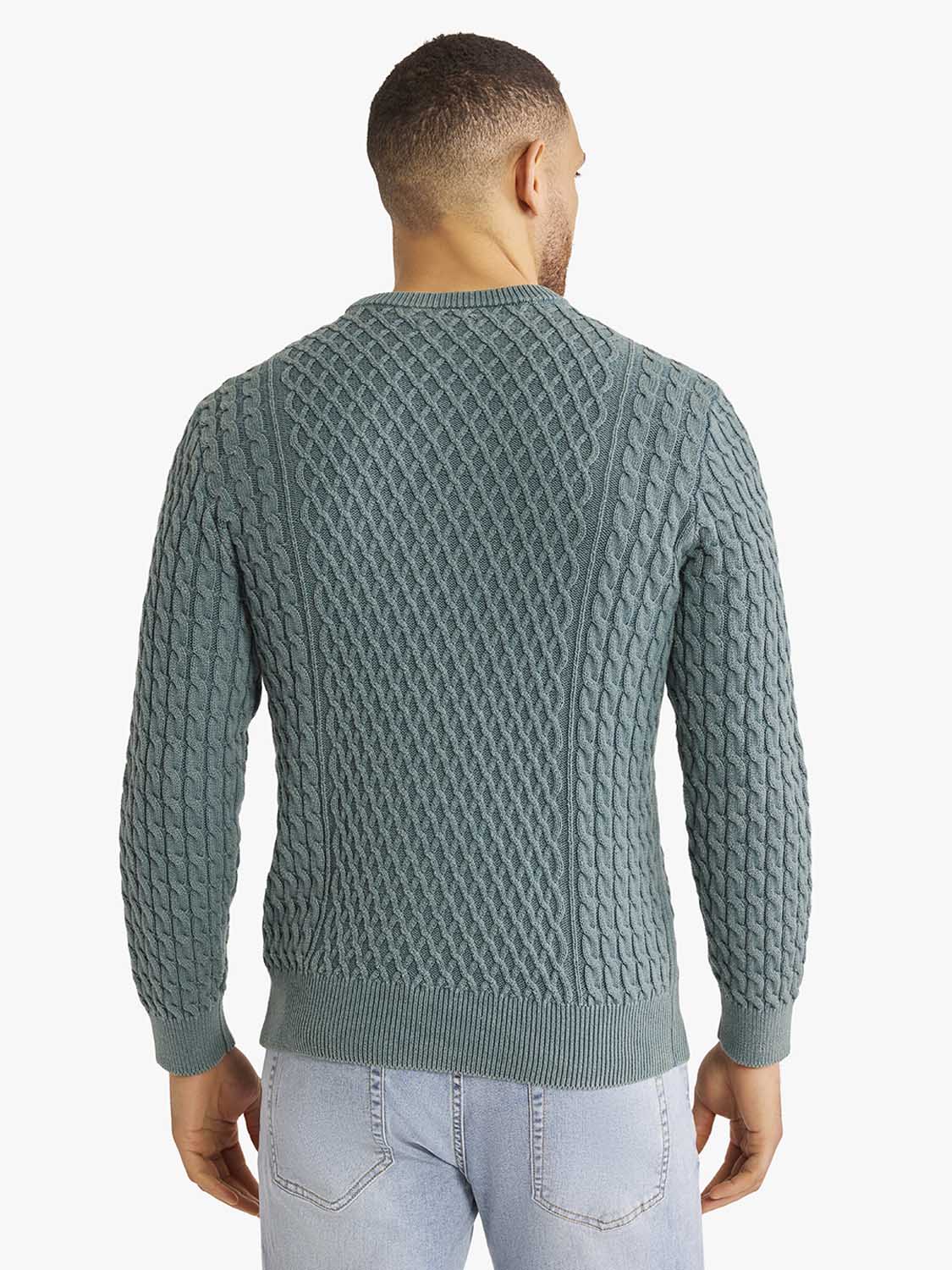 Man wearing a seapine green cable knit sweater with long sleeves and ribbed cuffs from behind.