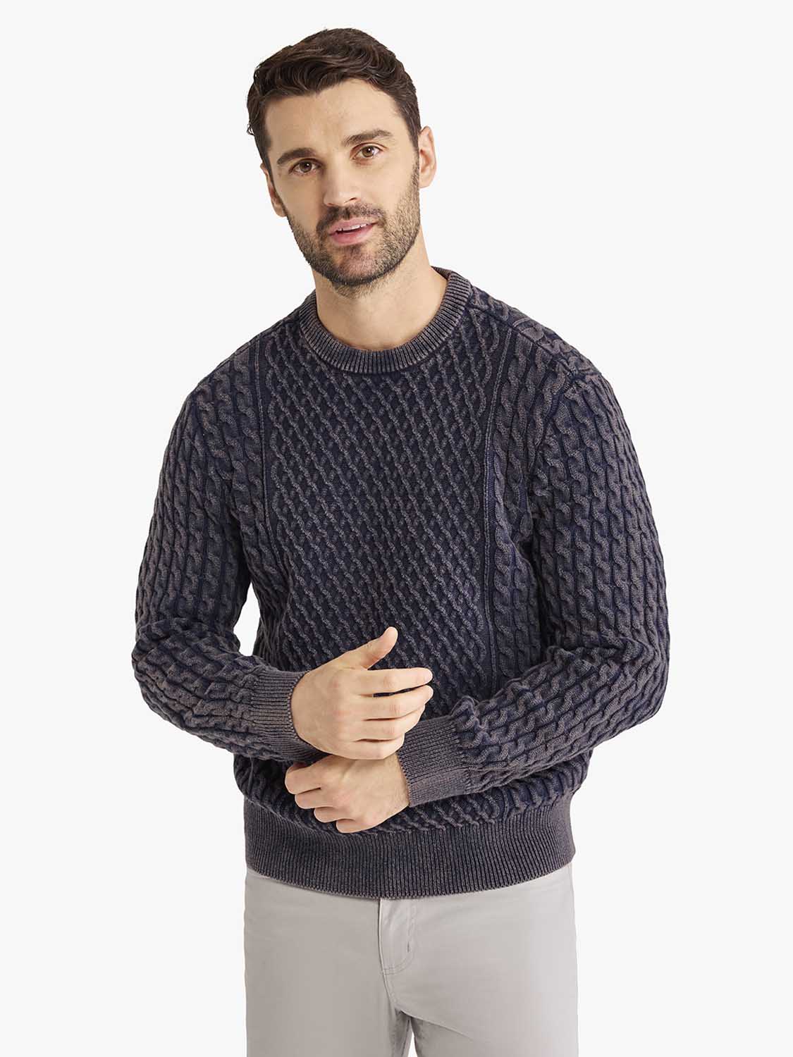 Man wearing navy cable knit sweater with ribbed crew neckline and cuffs.