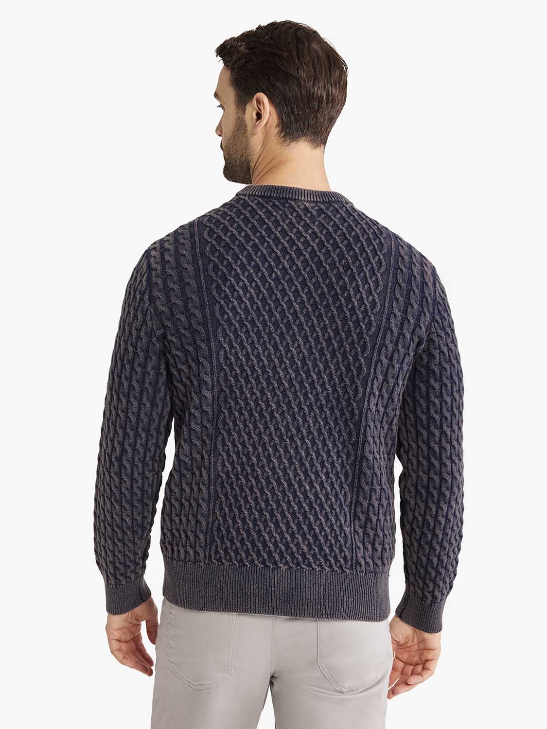 Man wearing a navy cable knit sweater with a crew neckline, viewed from the back.
