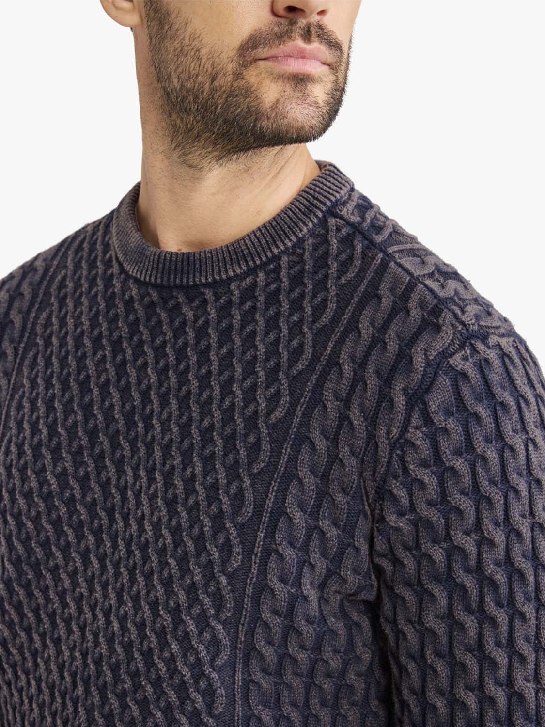 Man wearing navy cable knit sweater with crew neckline and textured pattern detail.