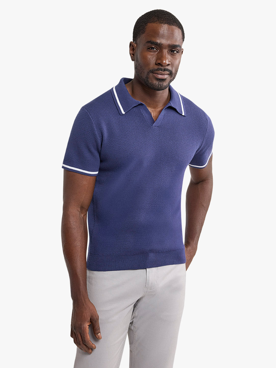 Man wearing navy short-sleeve polo sweater with white trim and light gray pants.