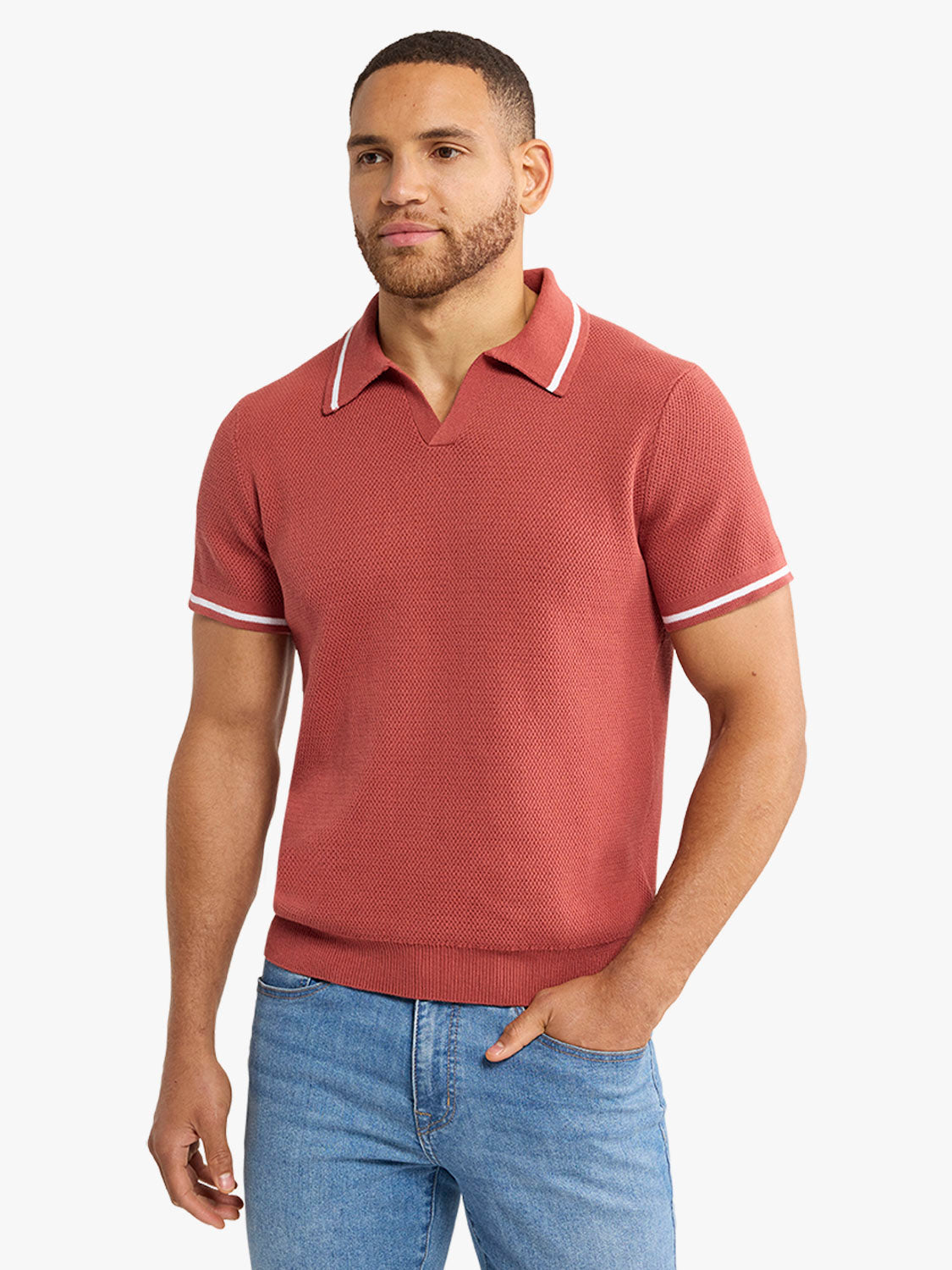Man wearing a washed red sweater polo with white striping on the collar and sleeves.