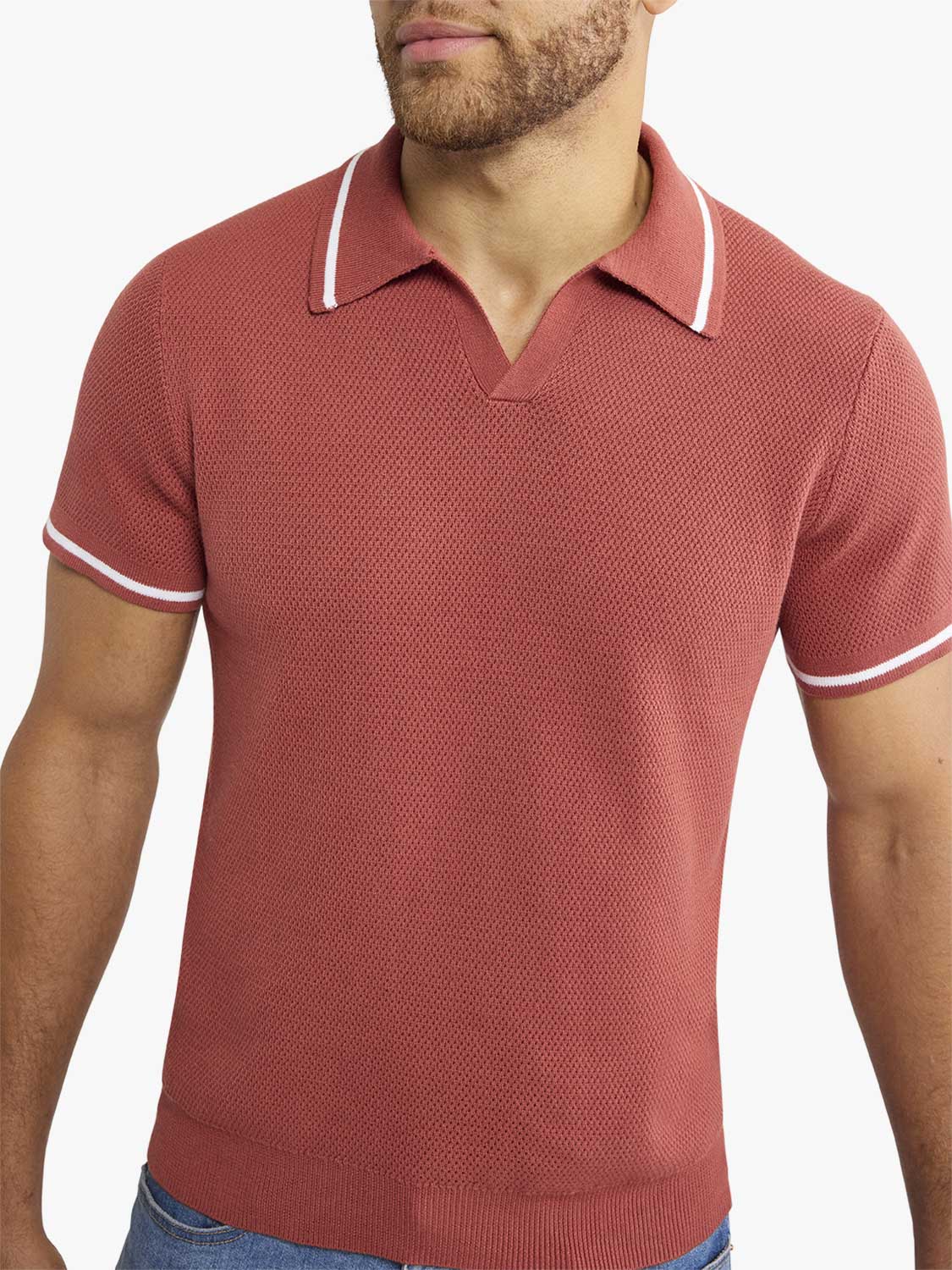 Man wearing a washed red sweater polo with white-tipped collar and short sleeves.