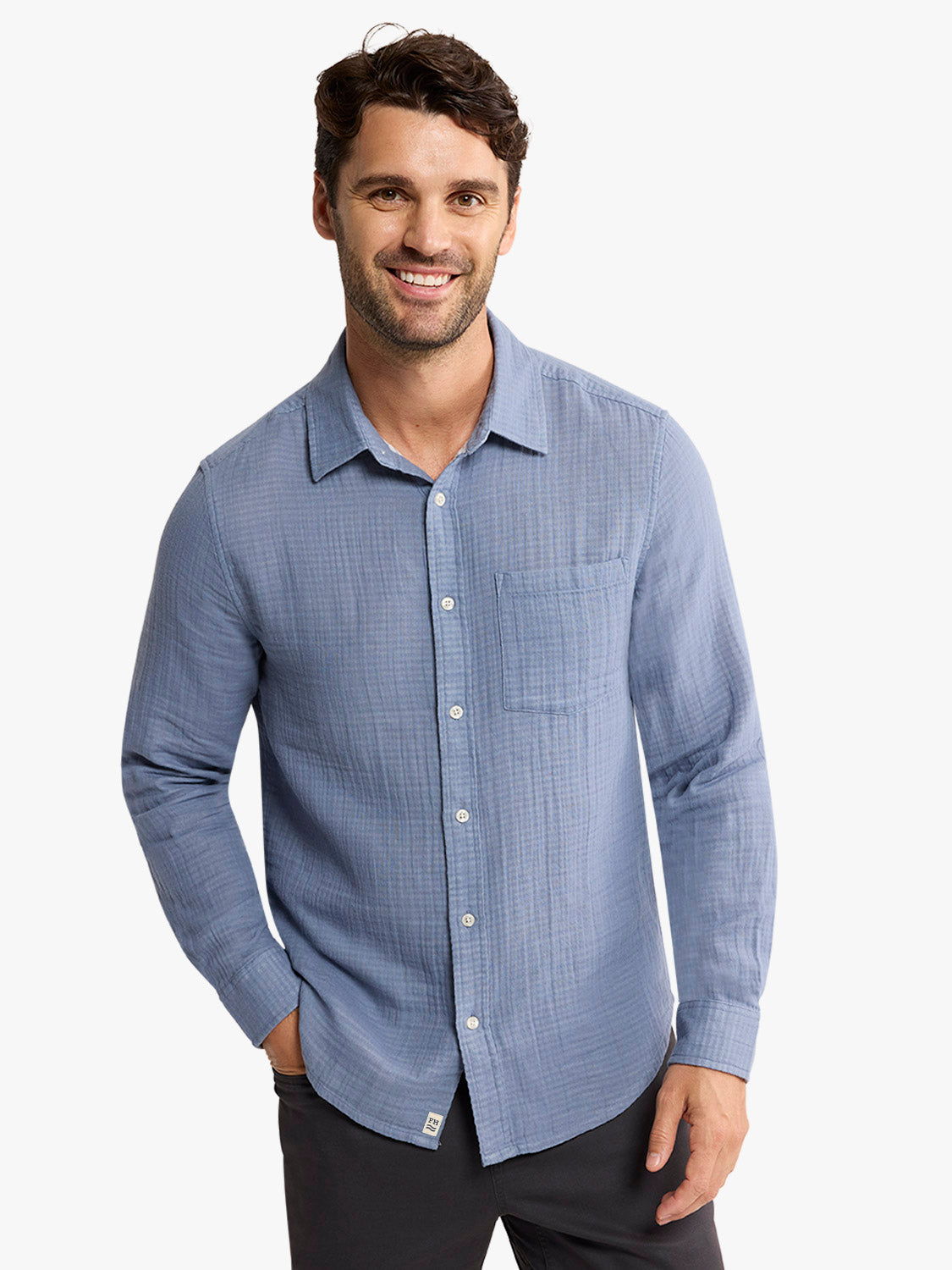 Man wearing a blue button-up shirt with long sleeves and a chest pocket.