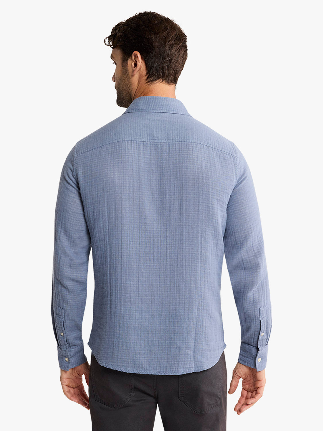 Man wearing a light blue long-sleeve button-up shirt with a textured weave pattern, shown from behind.