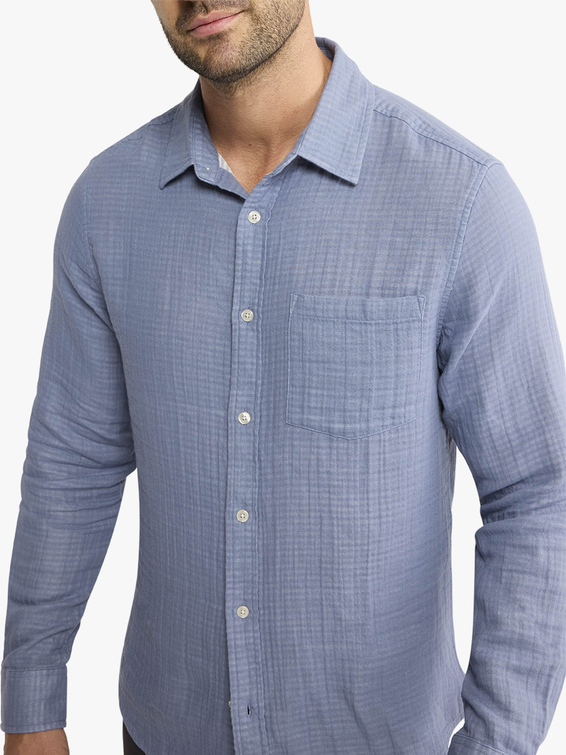 Man wearing a light blue button-up shirt with long sleeves and a chest pocket.