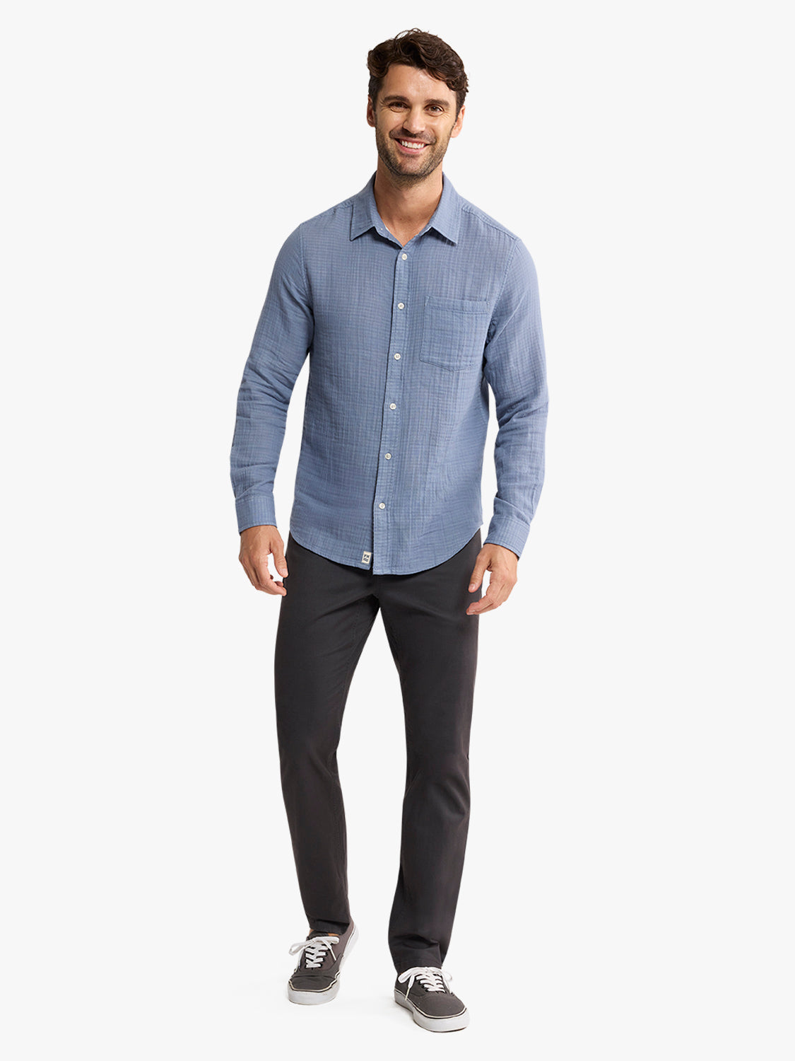 Man wearing a light blue button-up shirt with a chest pocket and black pants.