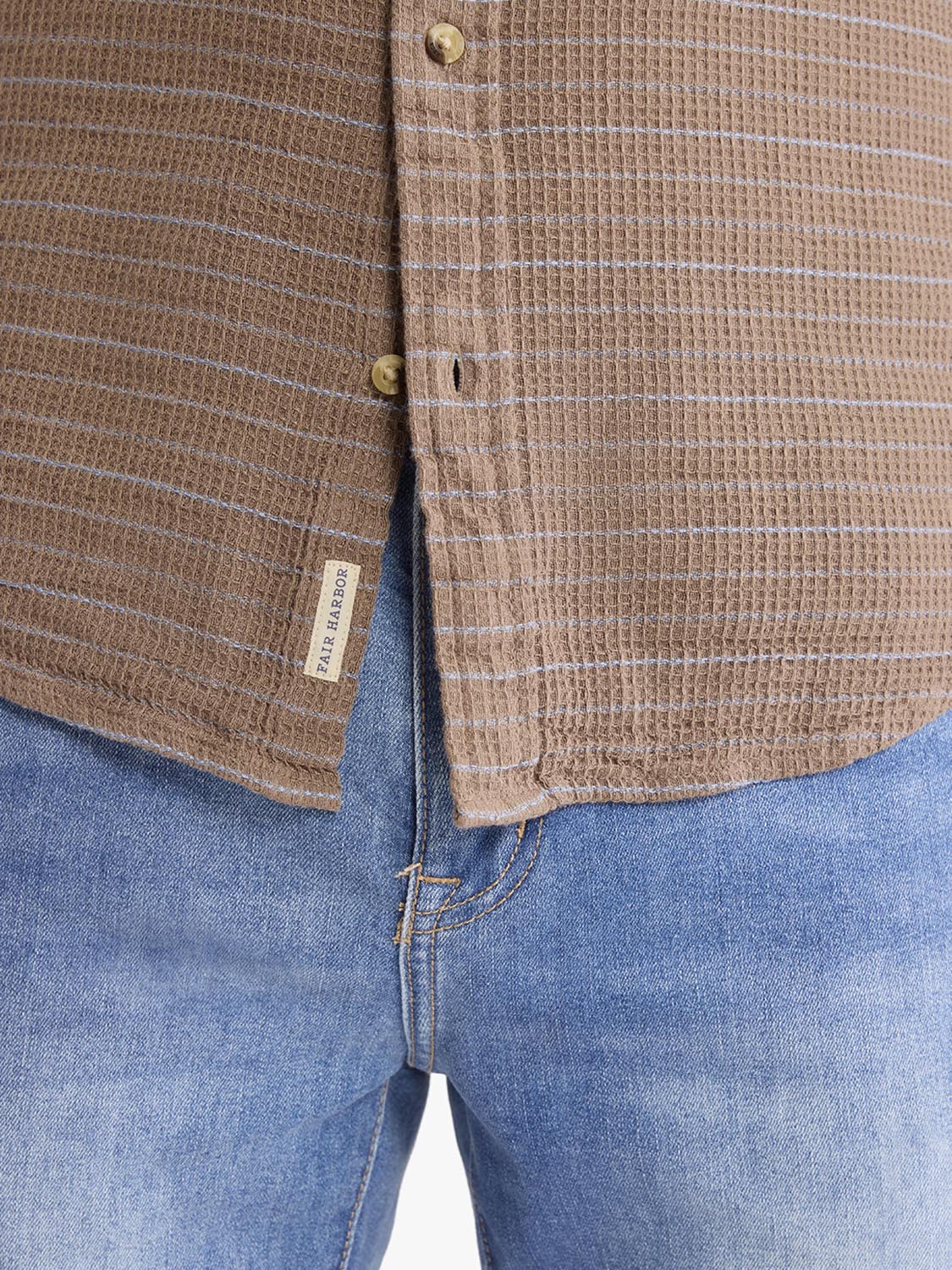 Beige waffle-striped long sleeve button-up shirt with gold buttons worn with blue denim jeans.