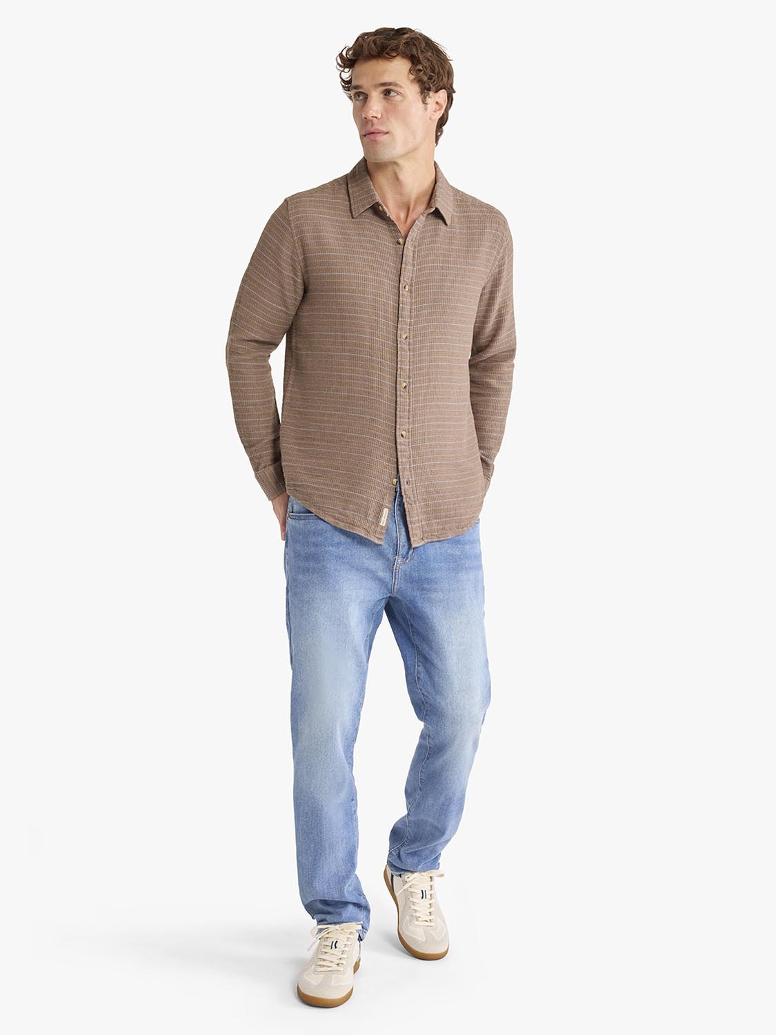 Man wearing a sandbar waffle stripe long sleeve button-up shirt and blue jeans.