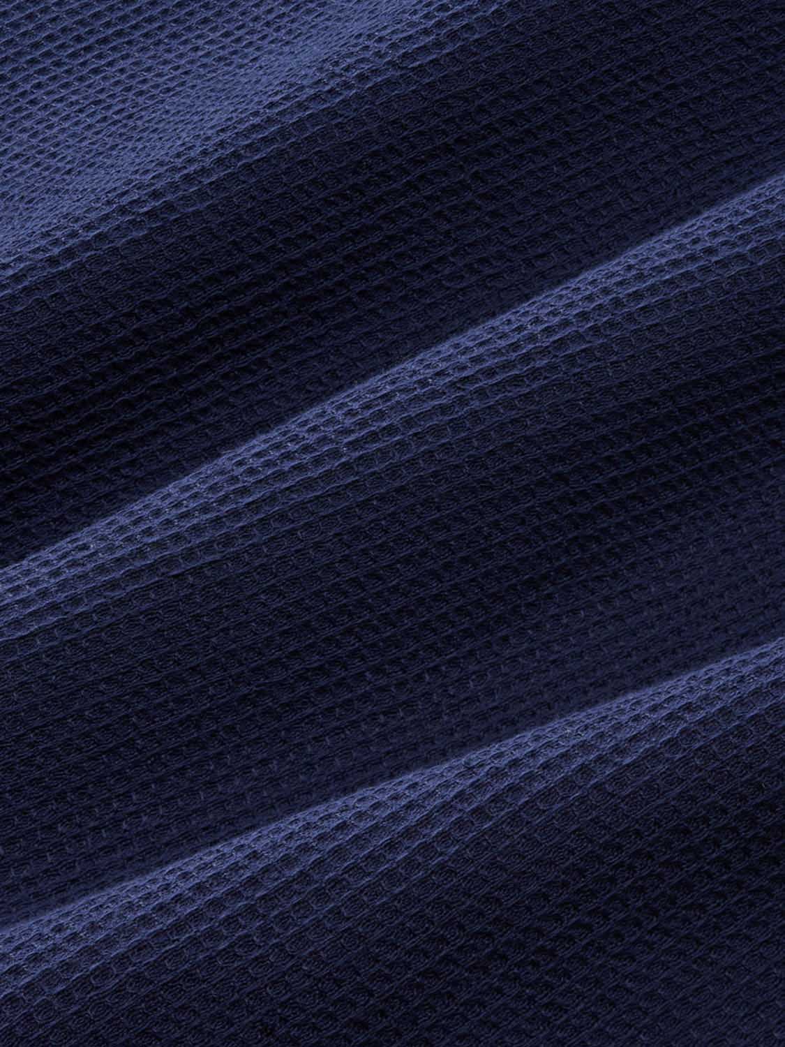 Navy waffle textured fabric showing diagonal folds and the raised grid weave pattern throughout.