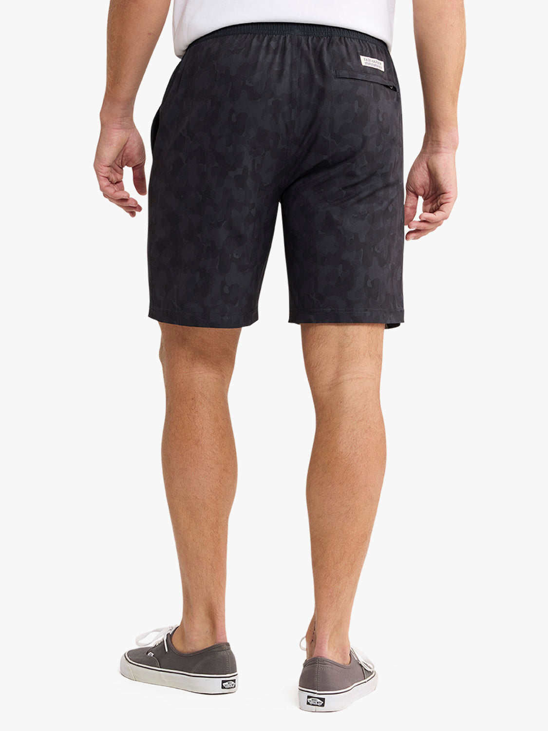 Man wearing black camouflage shorts with elastic waistband and back pocket detail.