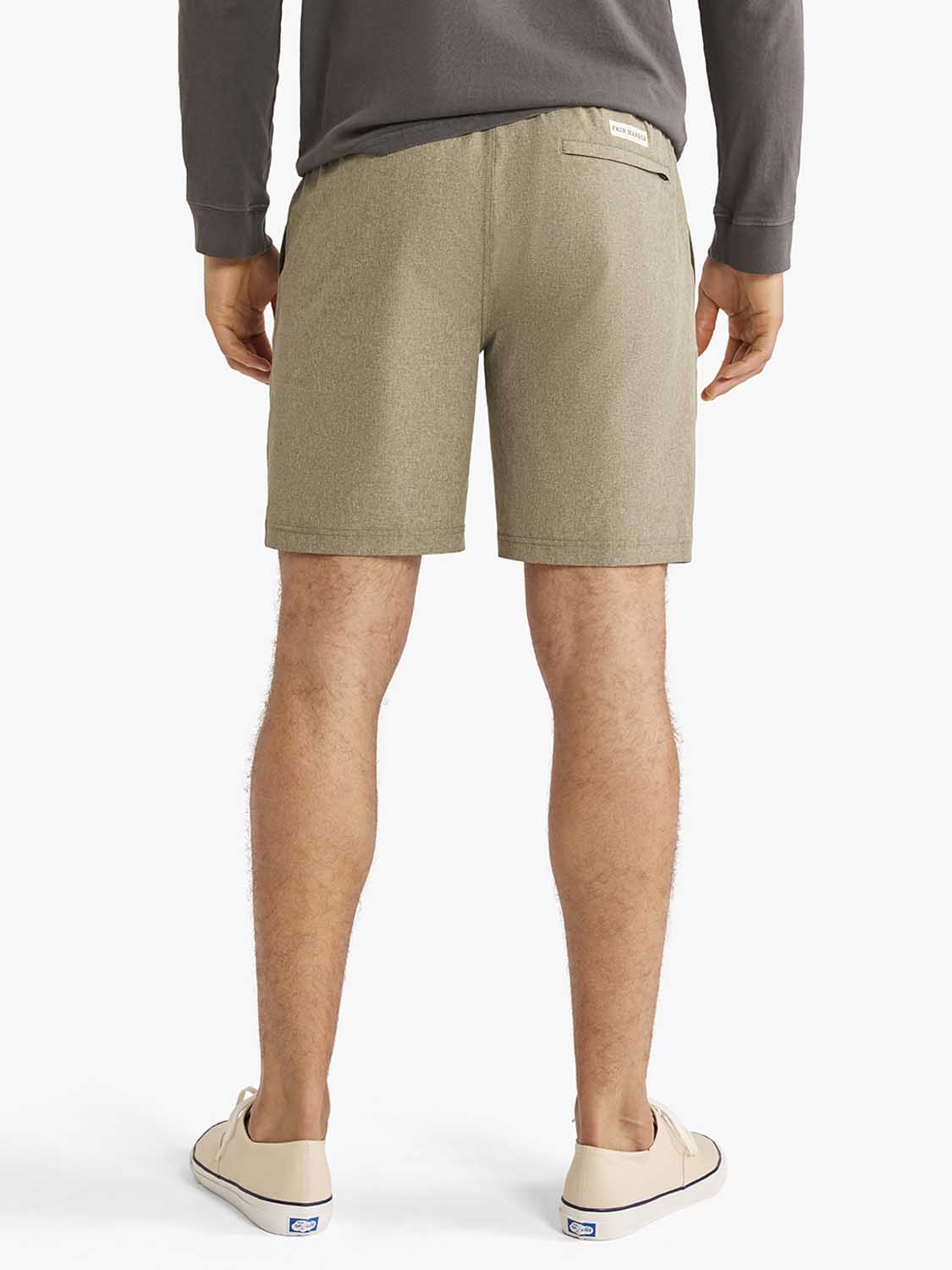 Man wearing olive heathered shorts and a gray long-sleeved shirt standing outdoors.
