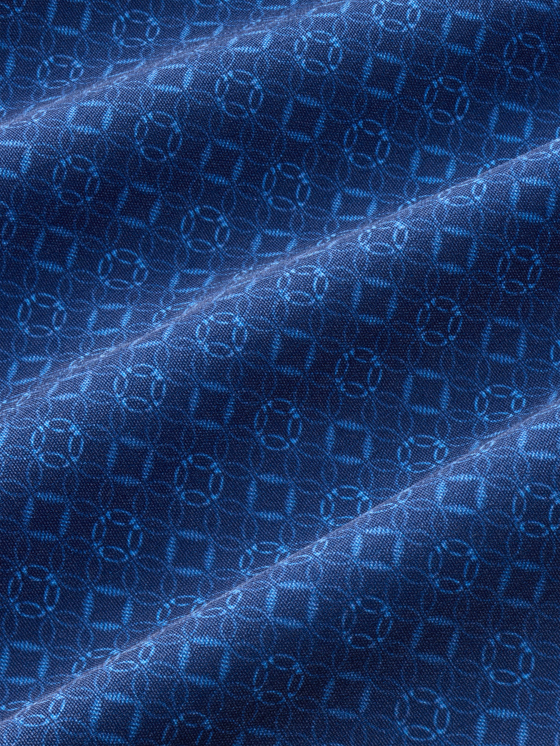 Blue fabric with repeating circular geometric patterns and diagonal seams across the surface.
