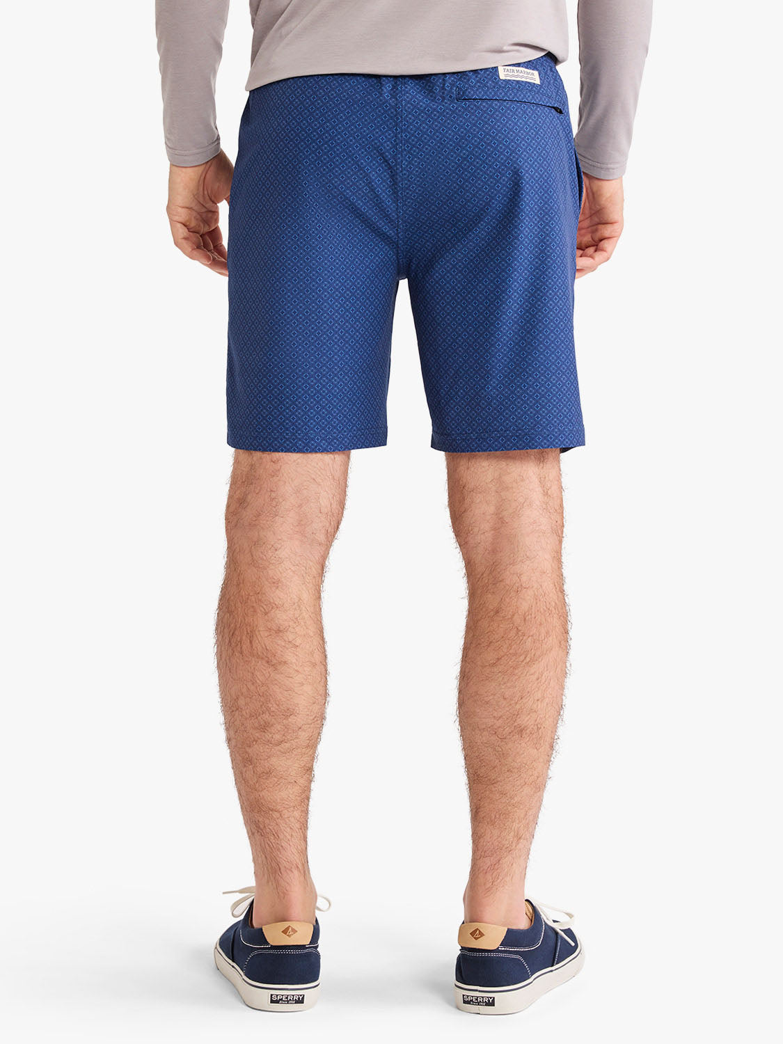 Man wearing blue shorts with circular pattern design viewed from behind.