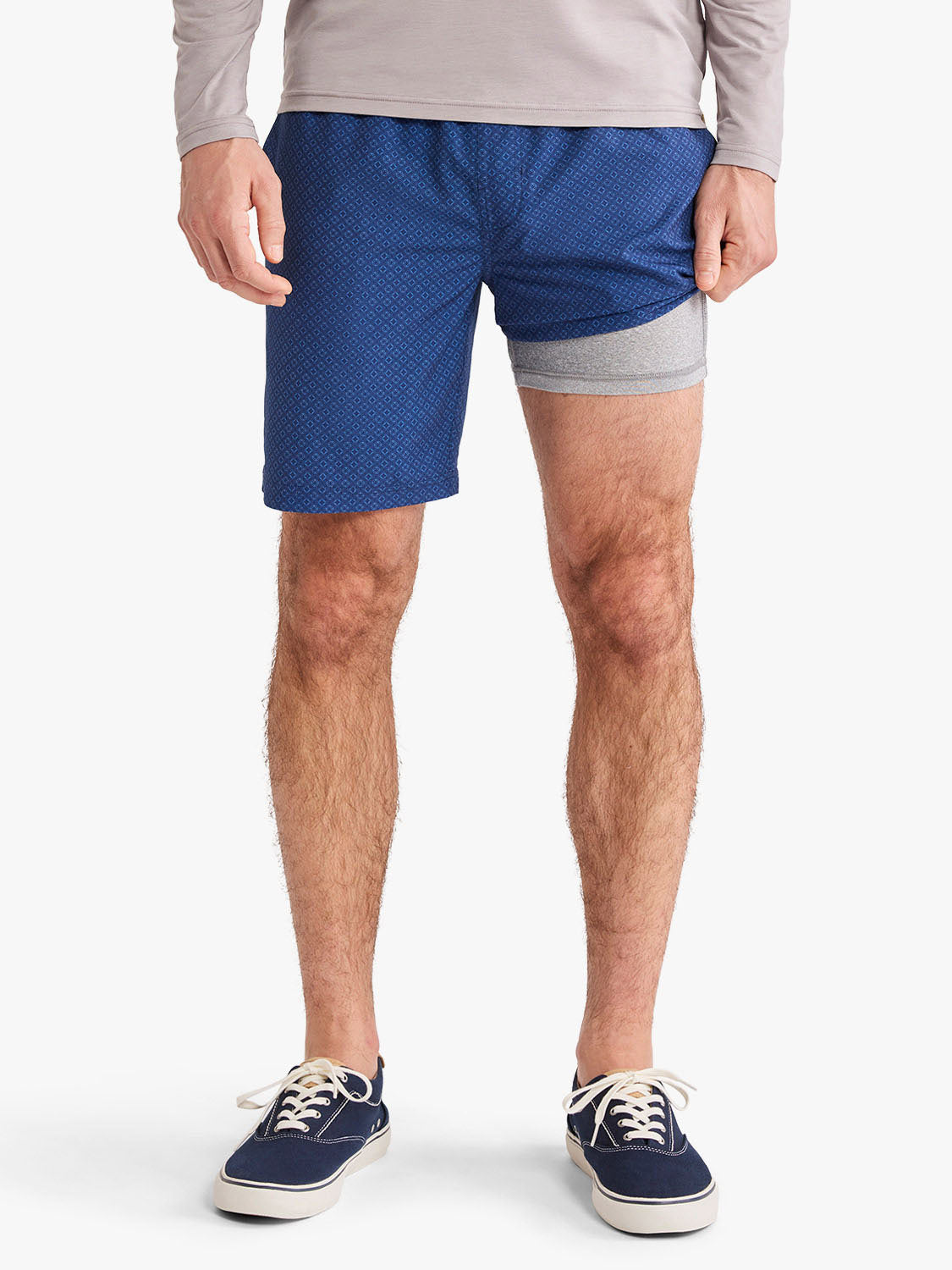 Man wearing blue shorts with small circle pattern and gray waistband trim.