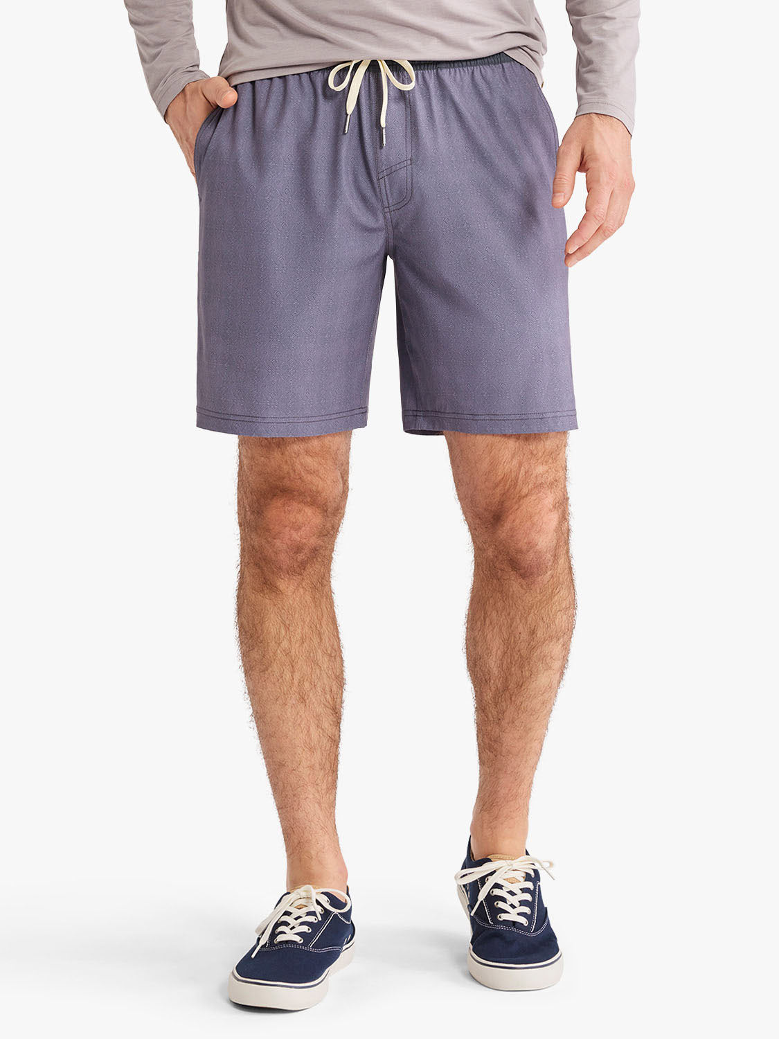Man wearing dusk purple shorts with drawstring waistband and side pockets paired with casual sneakers.