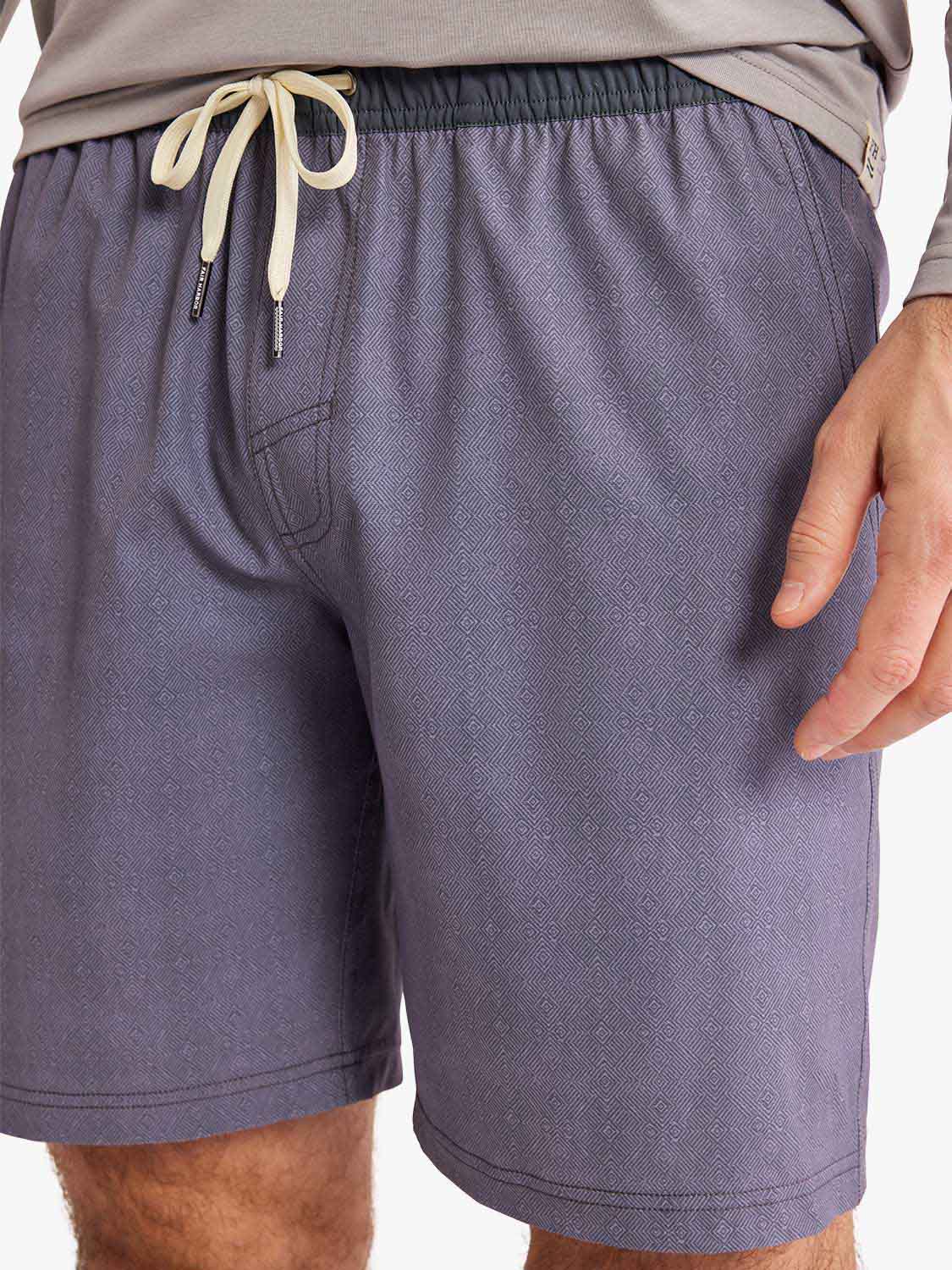 Purple textured shorts with cream drawstring waistband and front pockets on model wearing gray shirt.