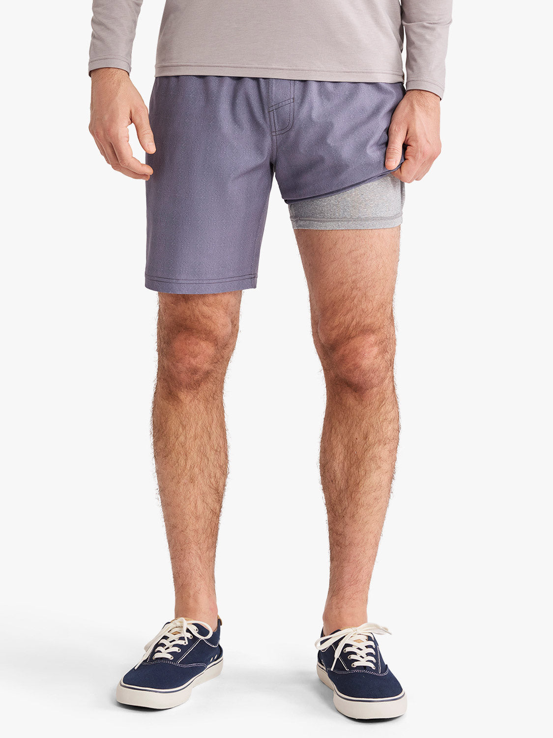 Man wearing dusk purple shorts with gray waistband and navy canvas sneakers.