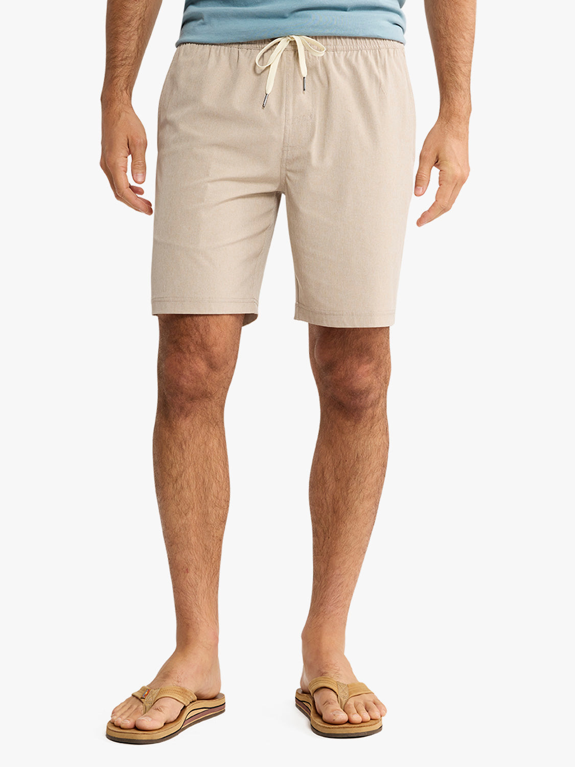 Man wearing khaki shorts with a drawstring waistband and tan sandals.