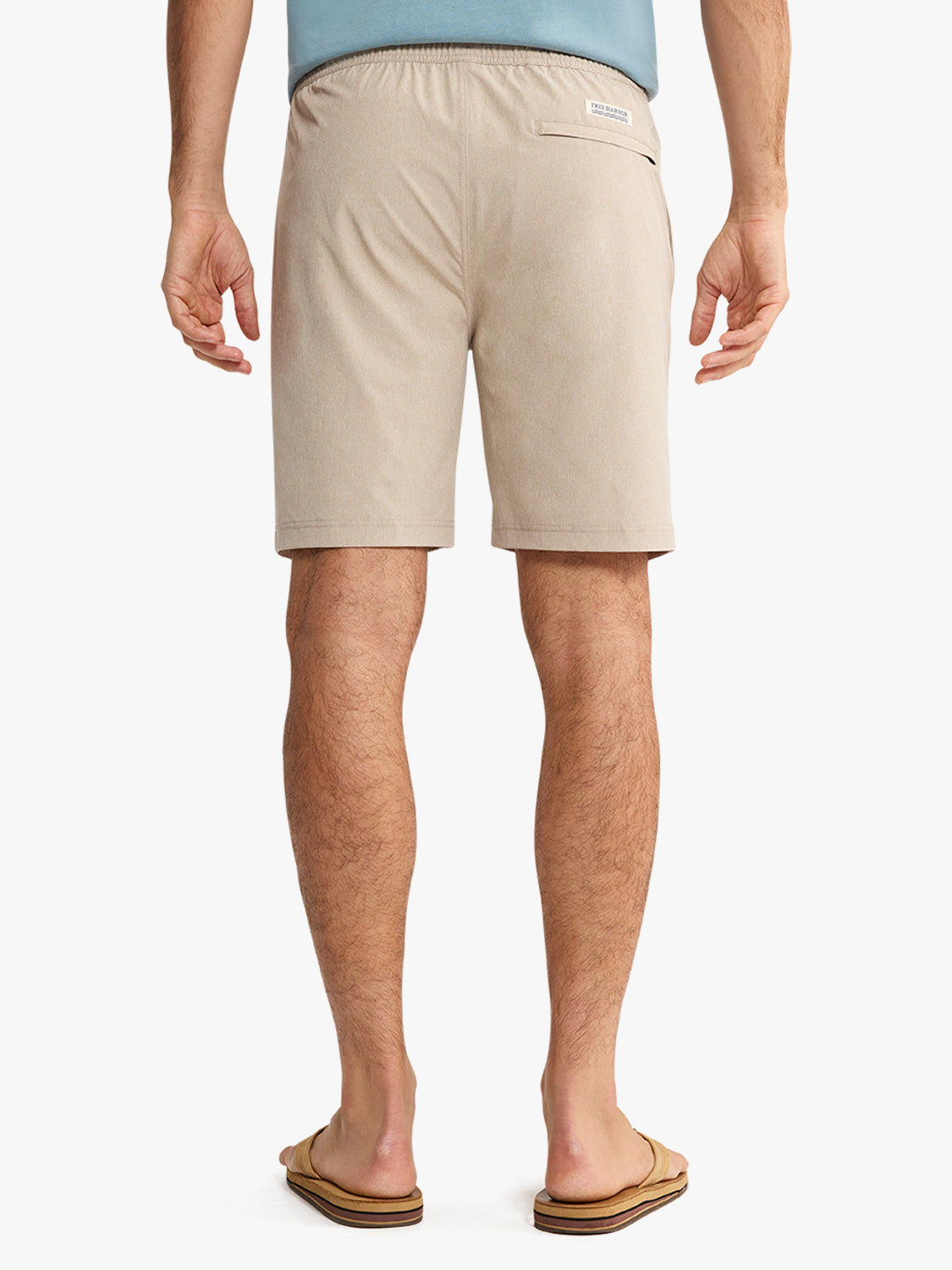 Man wearing khaki shorts with elastic waistband and back pocket label, paired with blue shirt.