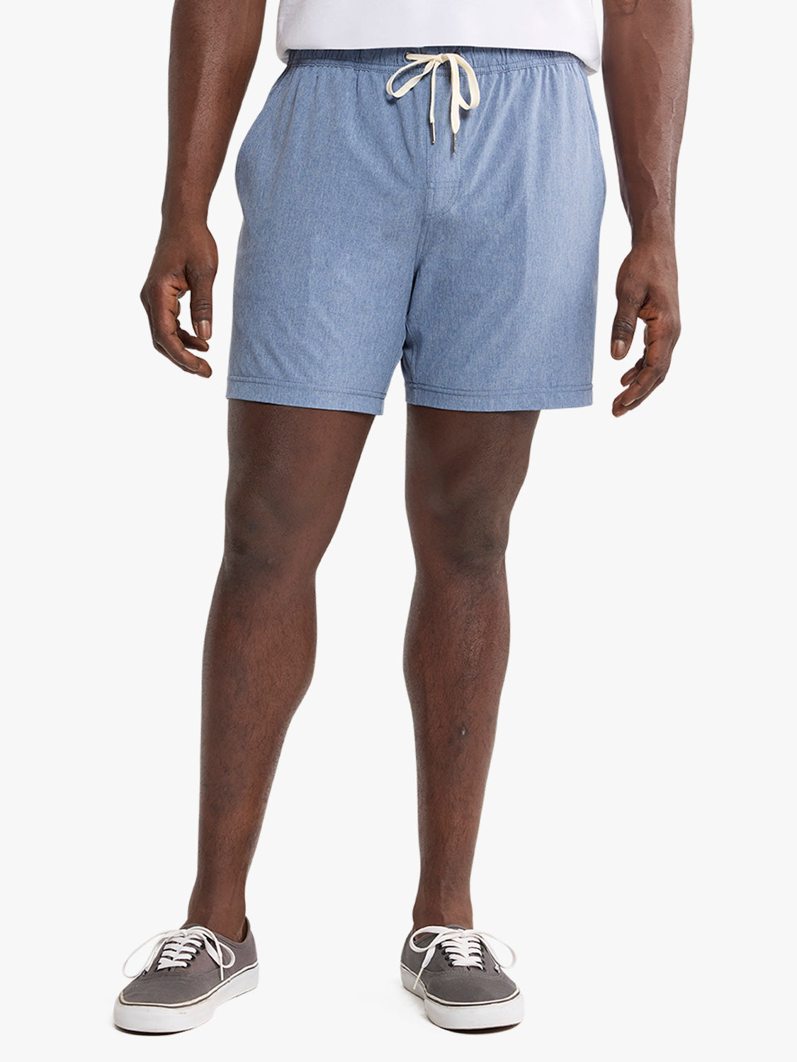 Man wearing light blue shorts with a drawstring waistband and white sneakers.