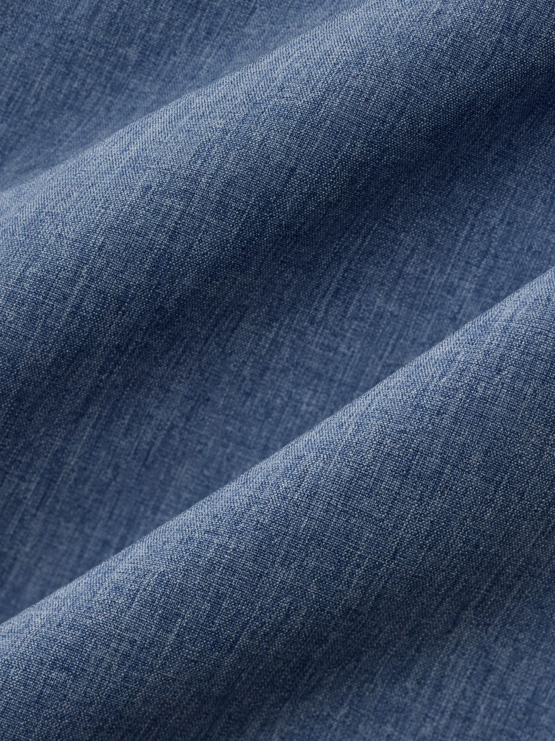 Blue fabric with a woven texture and diagonal folds creating light and shadow variations.